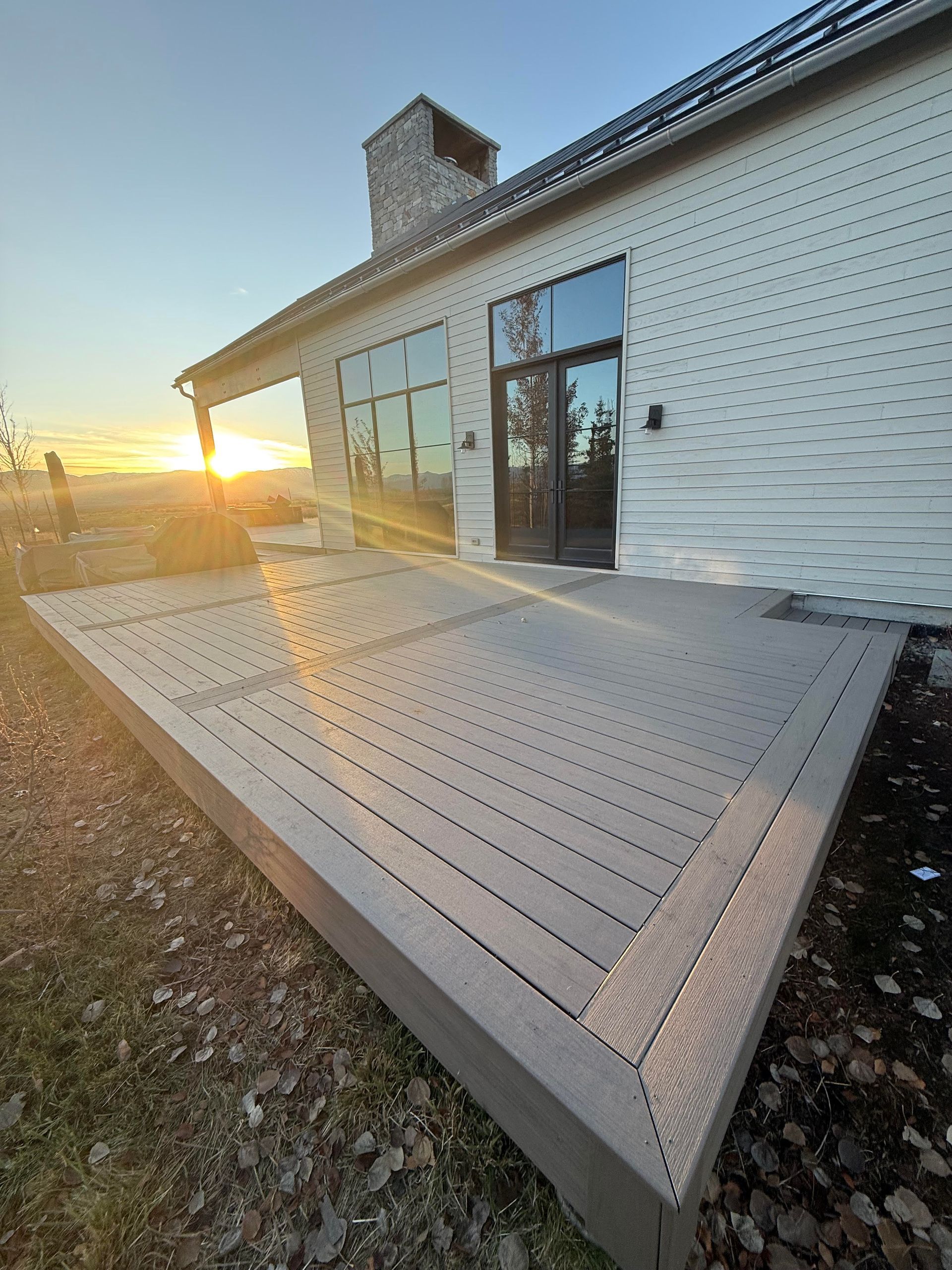 Wooden deck and patio beside a modern brick house at sunset