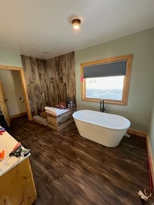 Bright bathroom with glass shower, toilet, vanity, patterned floor, and window light