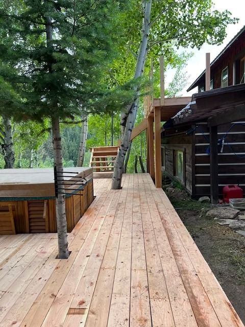 Wooden deck walkway beside trees and a cabin in a wooded outdoor setting