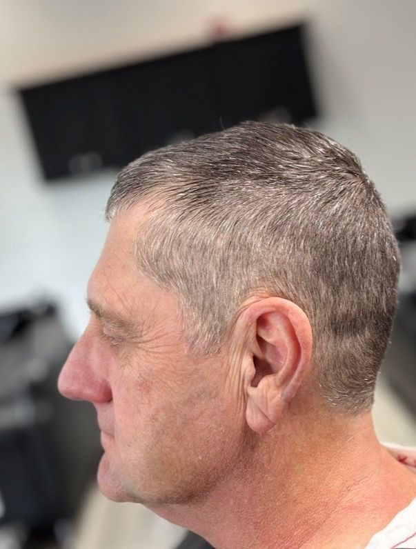 Side profile of a person with short, light-brown hair in a salon setting.
