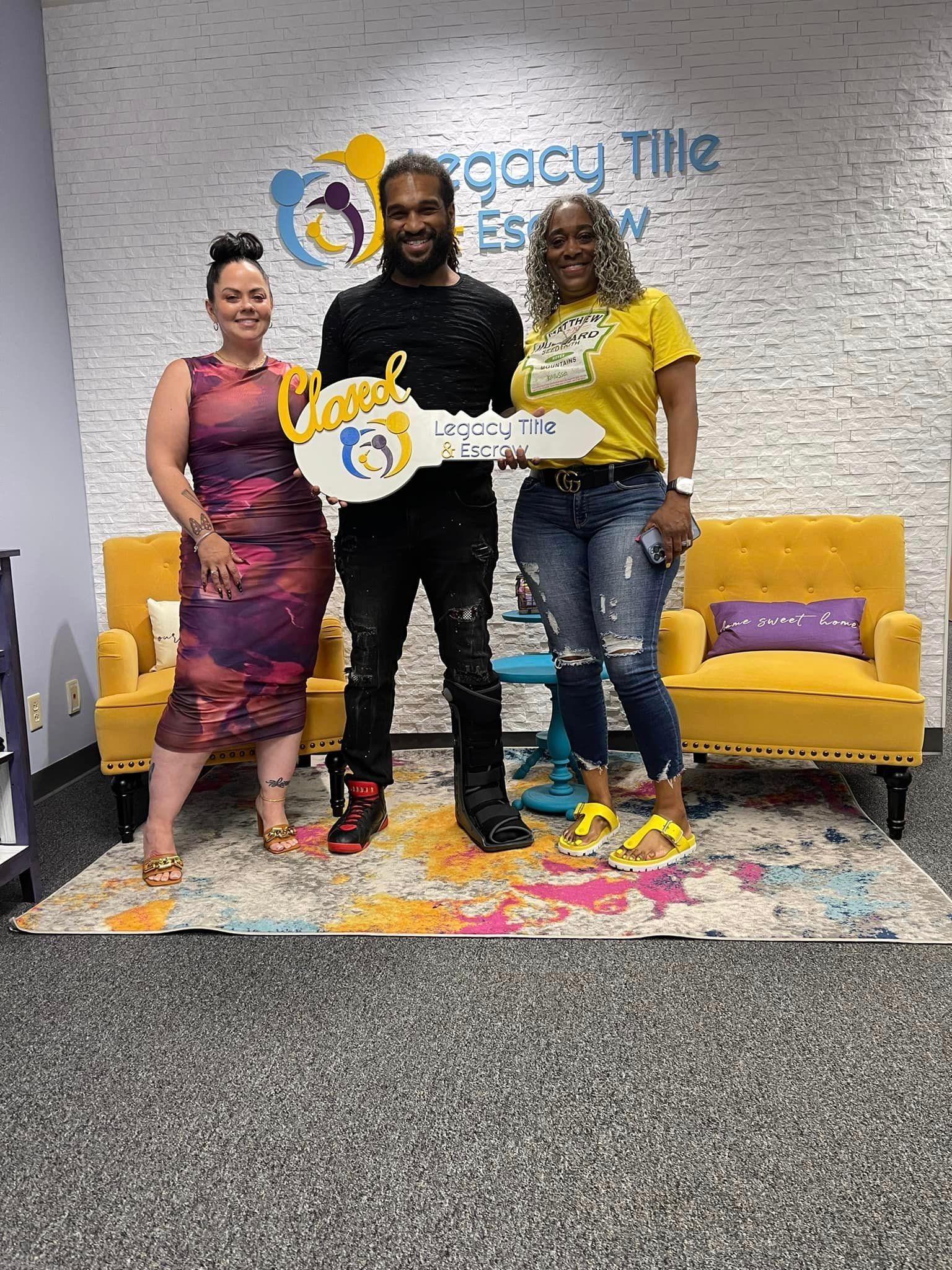 A man and two women are standing next to each other in a room holding keys.