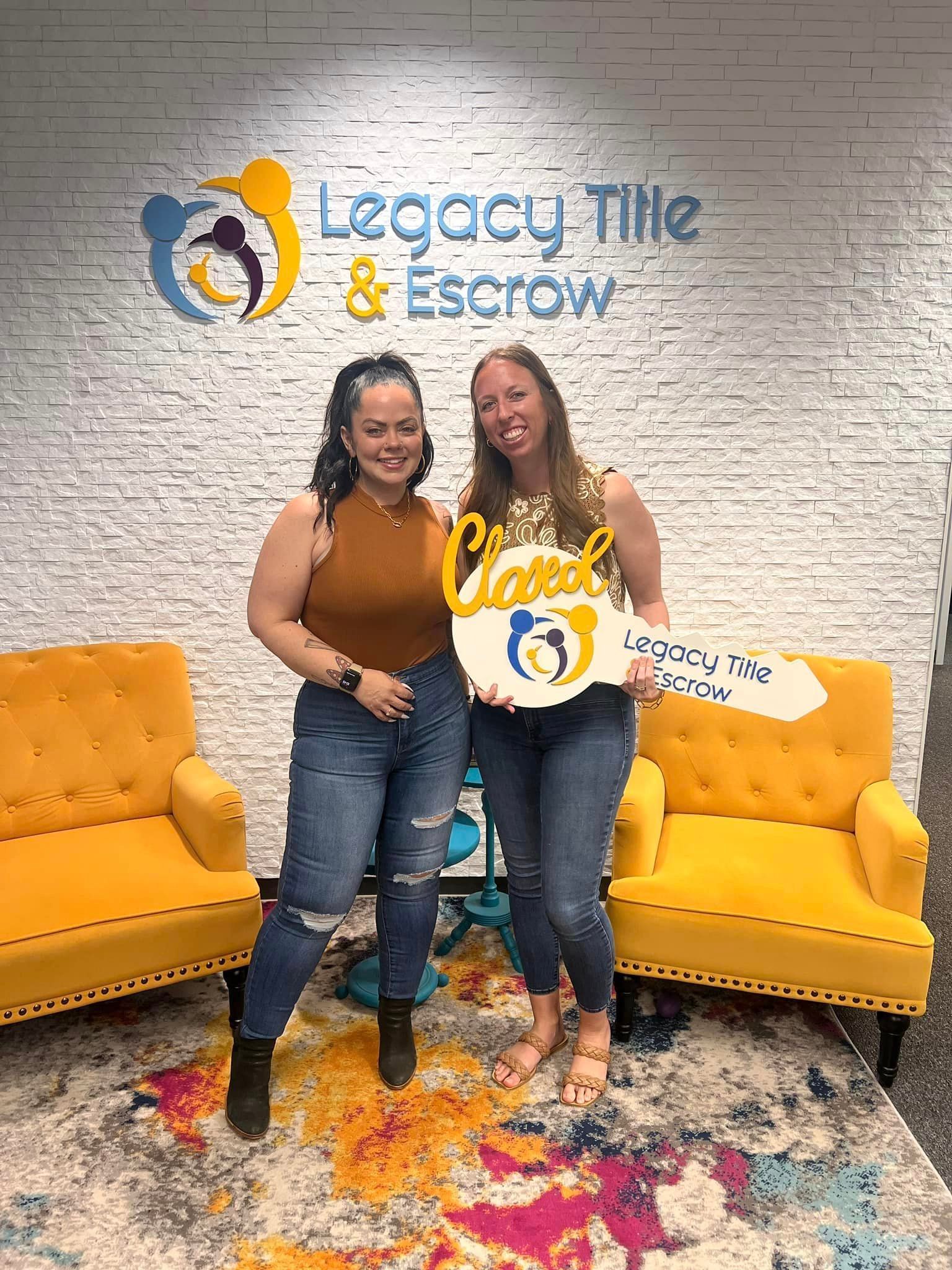 Two women are standing next to each other in a room holding a key.