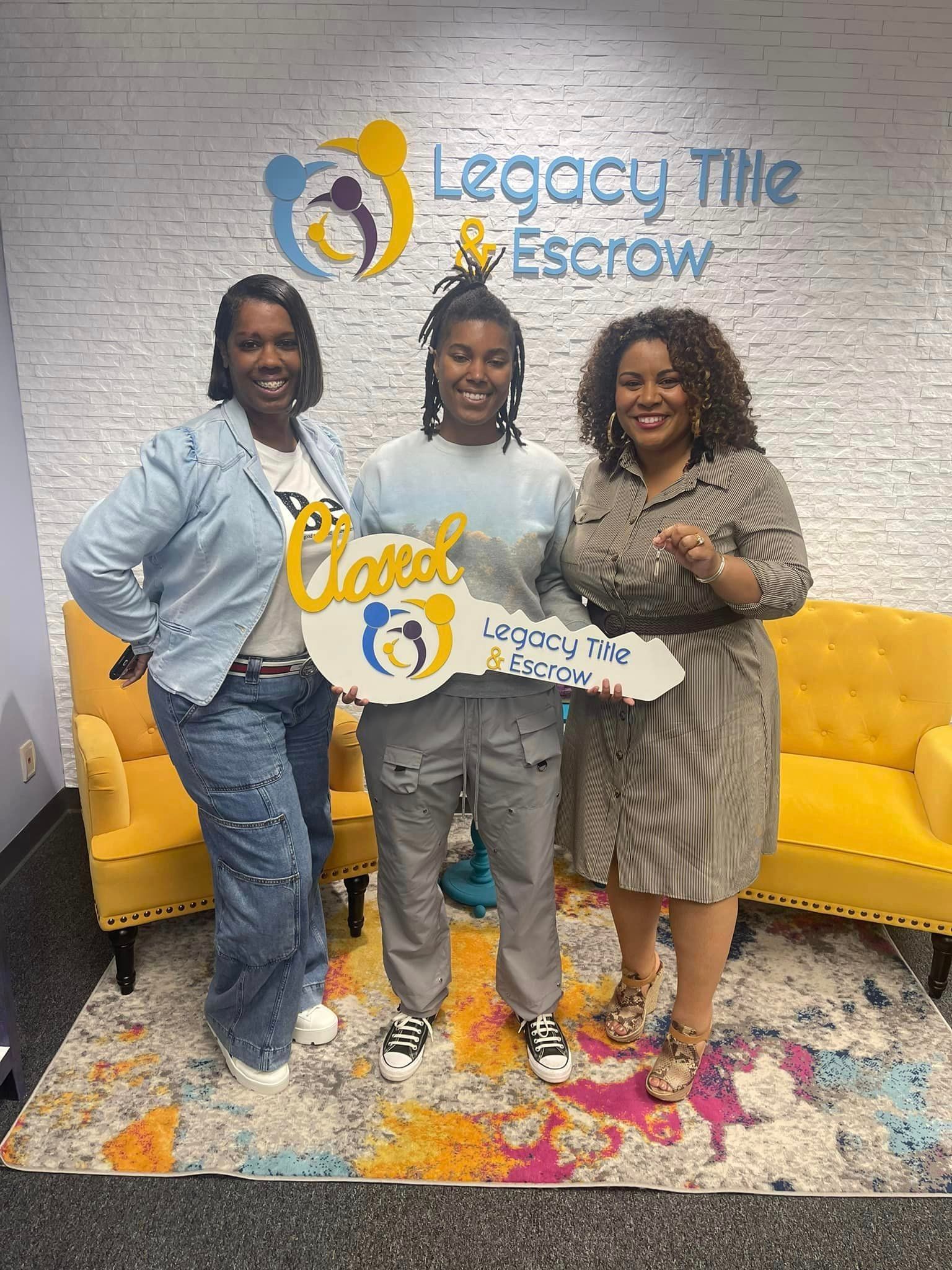 Three women are standing next to each other in a room holding a key.