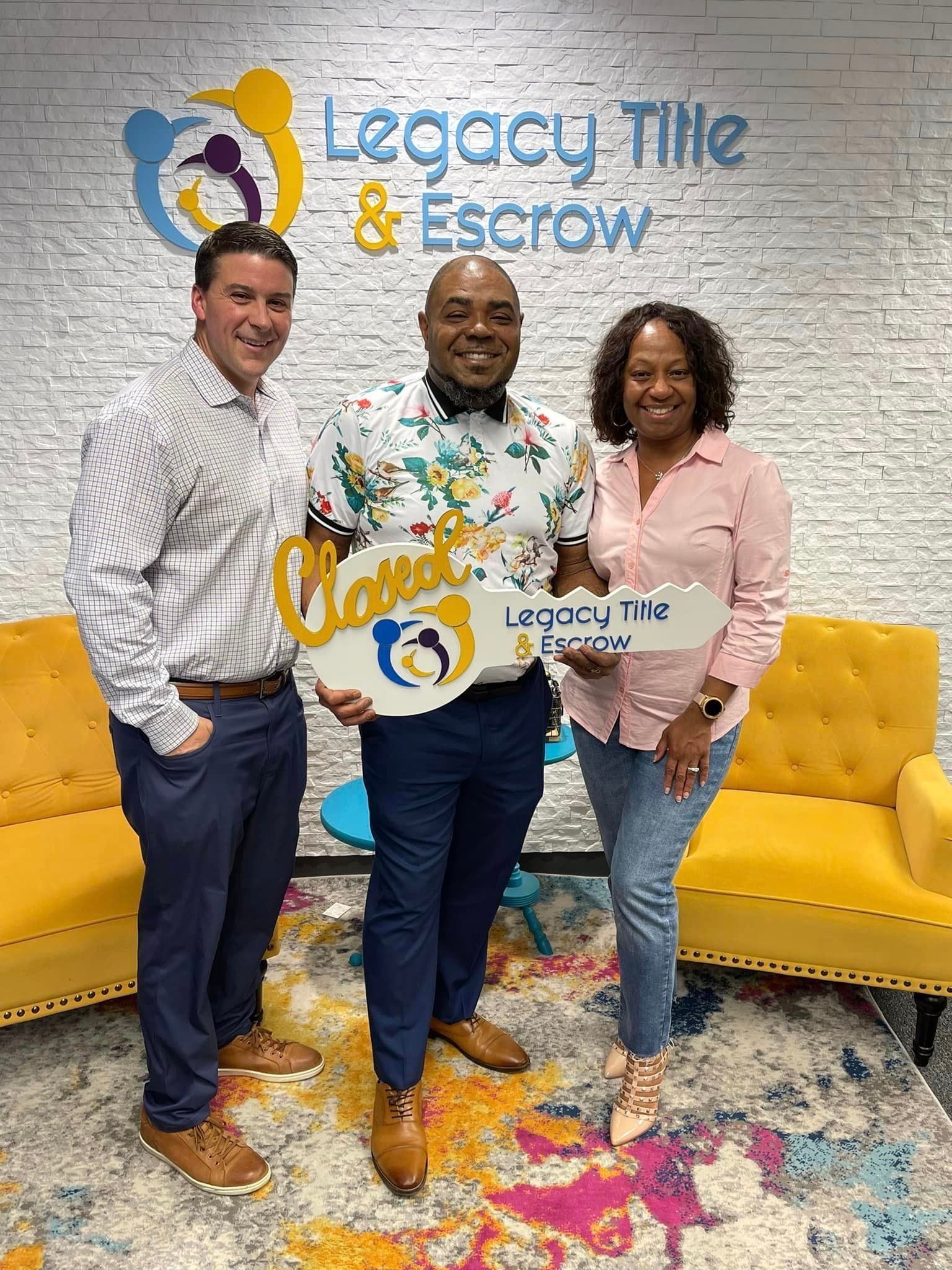 Three people are standing next to each other in a room holding a key.