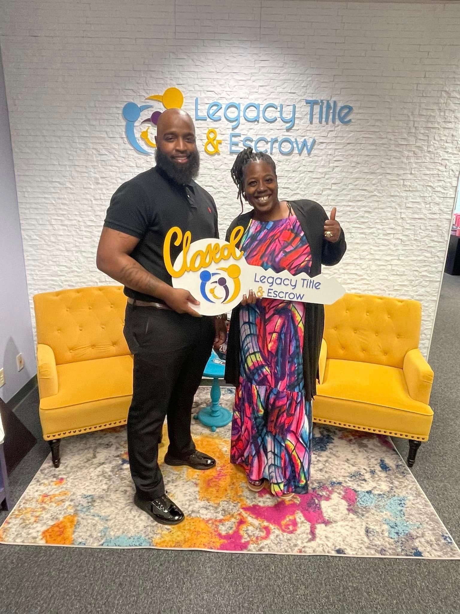 A man and a woman are standing next to each other in a room holding a sign.