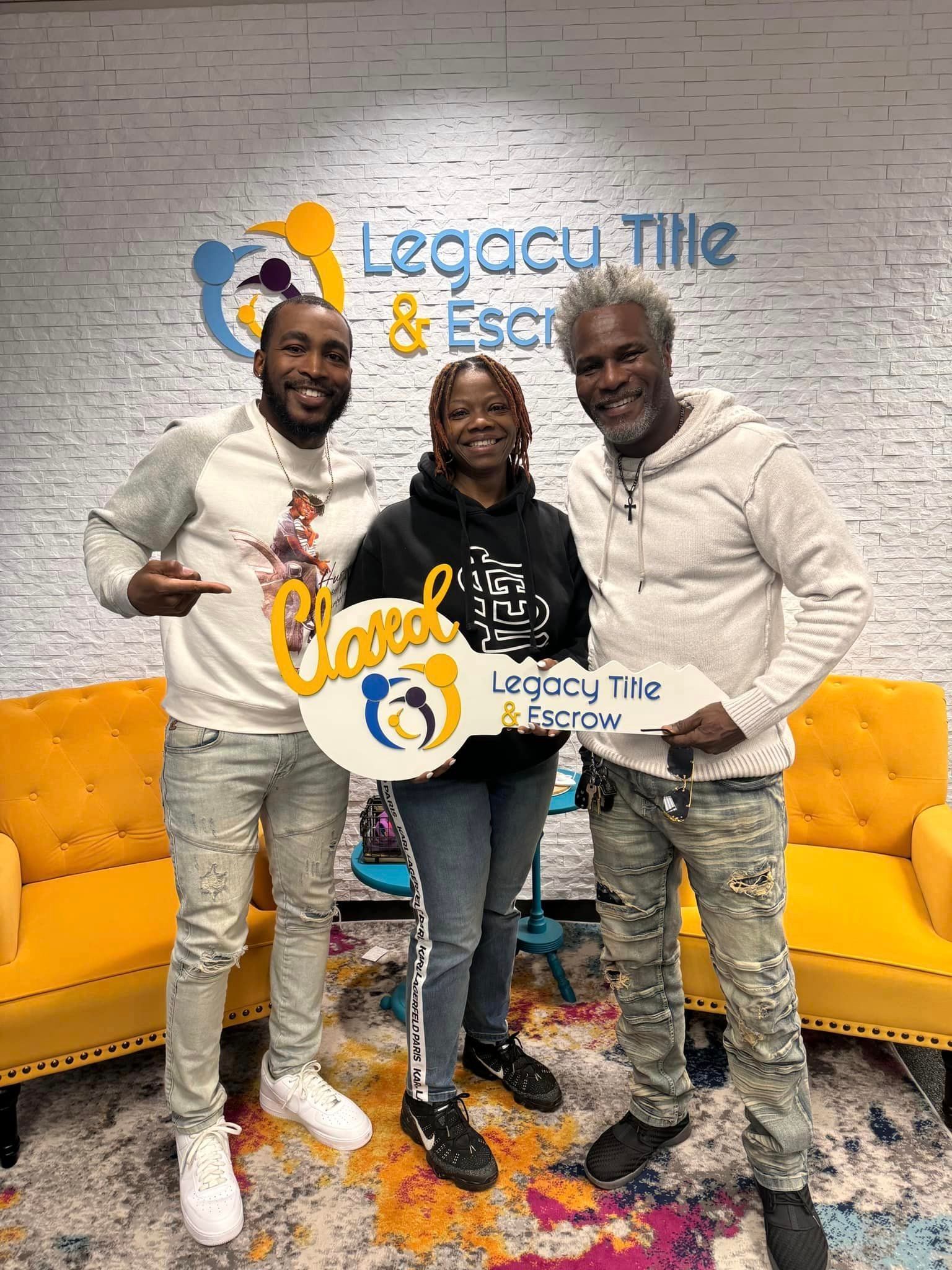 Three people are standing next to each other in a room holding a key.