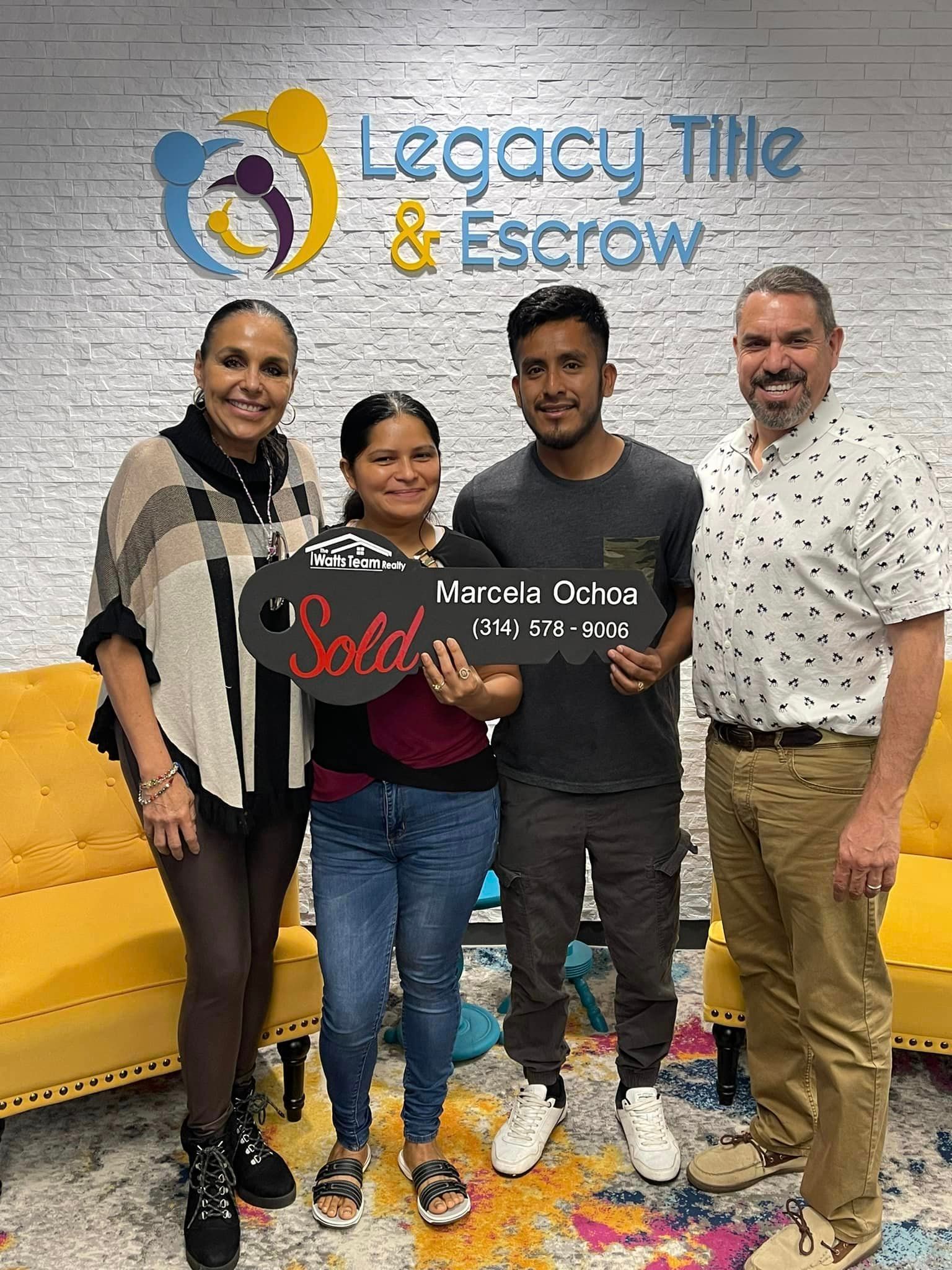 A group of people standing next to each other holding a sold sign.