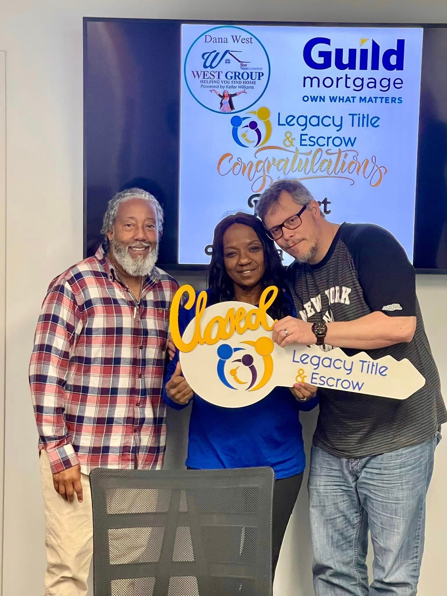 Three people are standing next to each other holding a key.