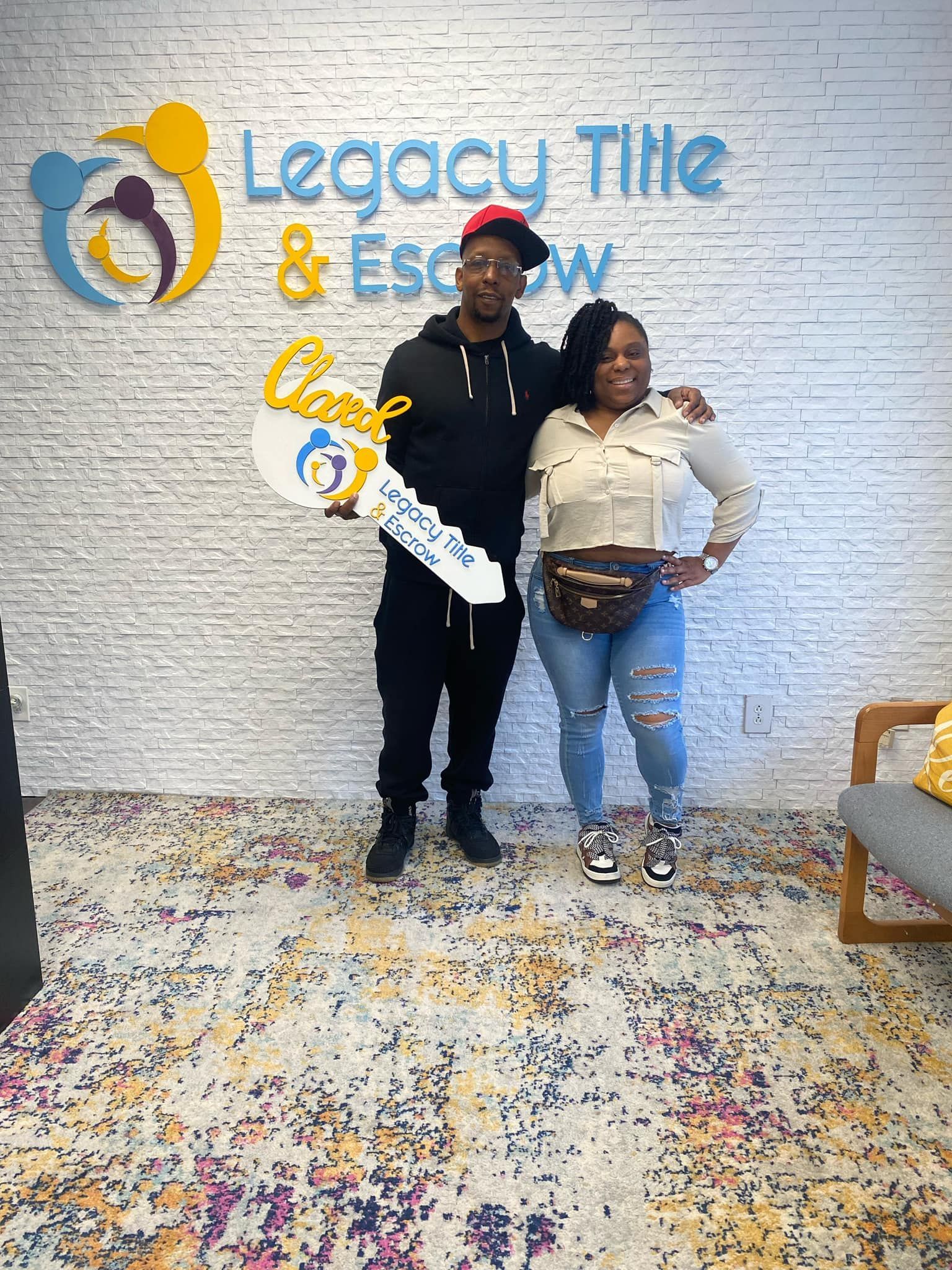 A man and a woman are standing next to each other in front of a brick wall holding a key.