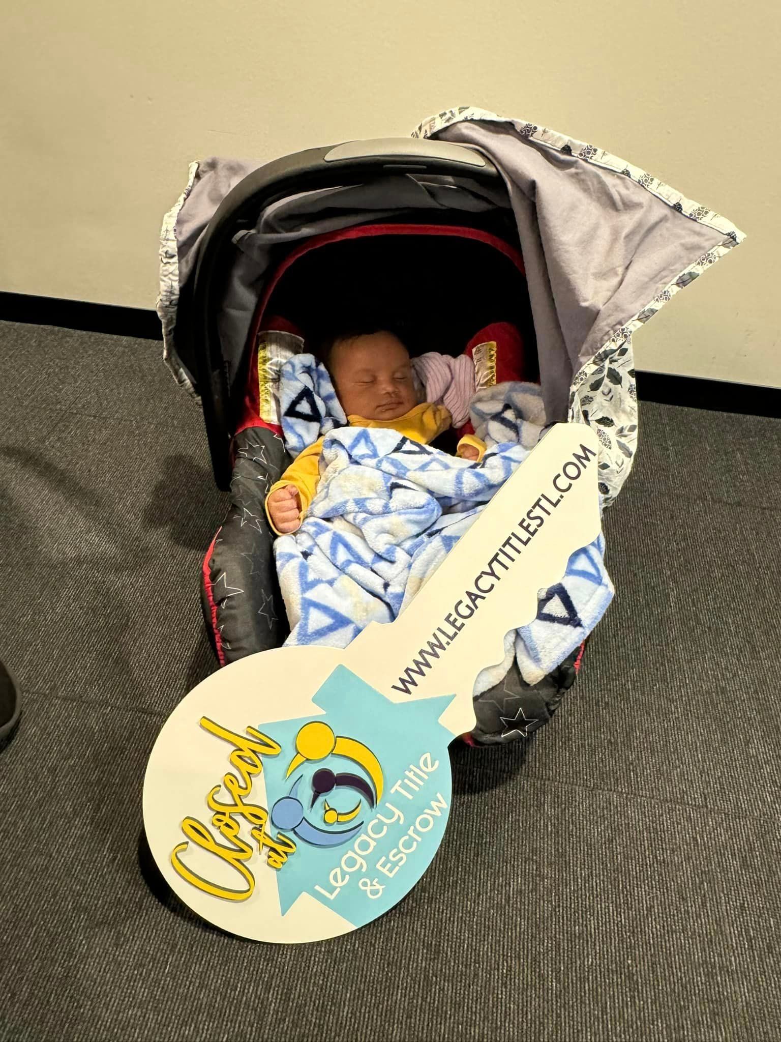 A baby is sitting in a stroller with a key on the floor.
