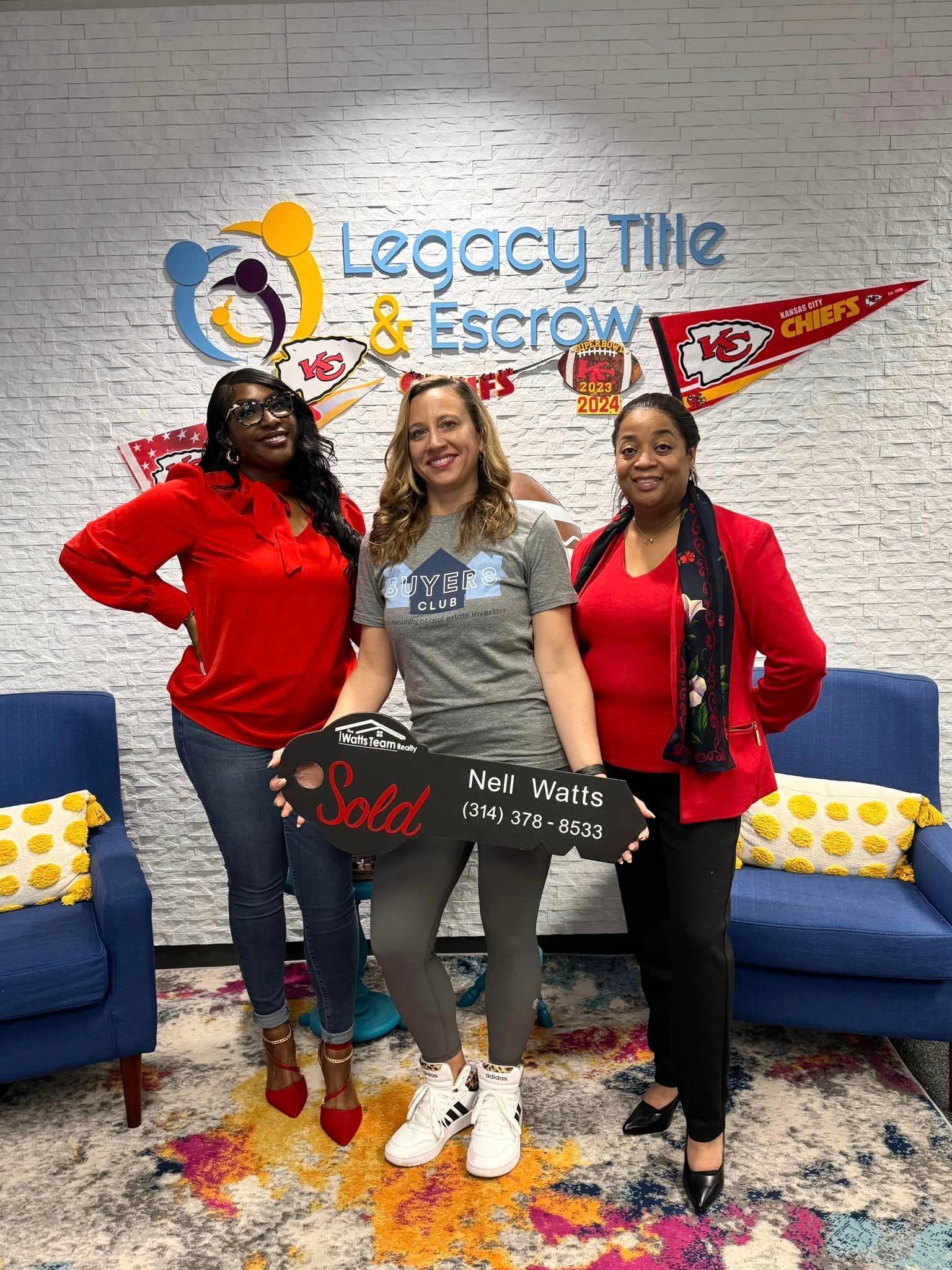 Three women are posing for a picture in front of a brick wall.