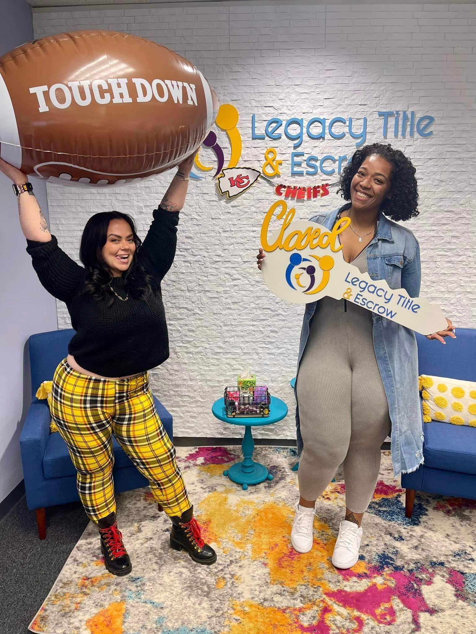 Two women are standing next to each other holding balloons and a key.