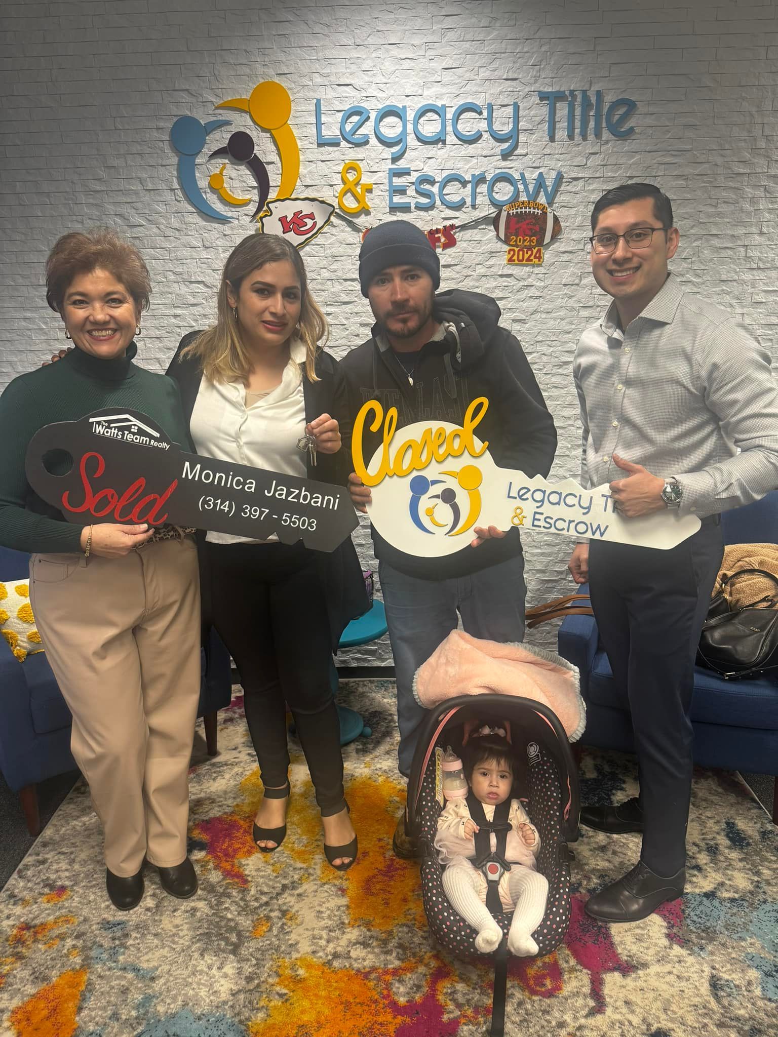 A group of people standing next to each other holding keys and a baby in a car seat.