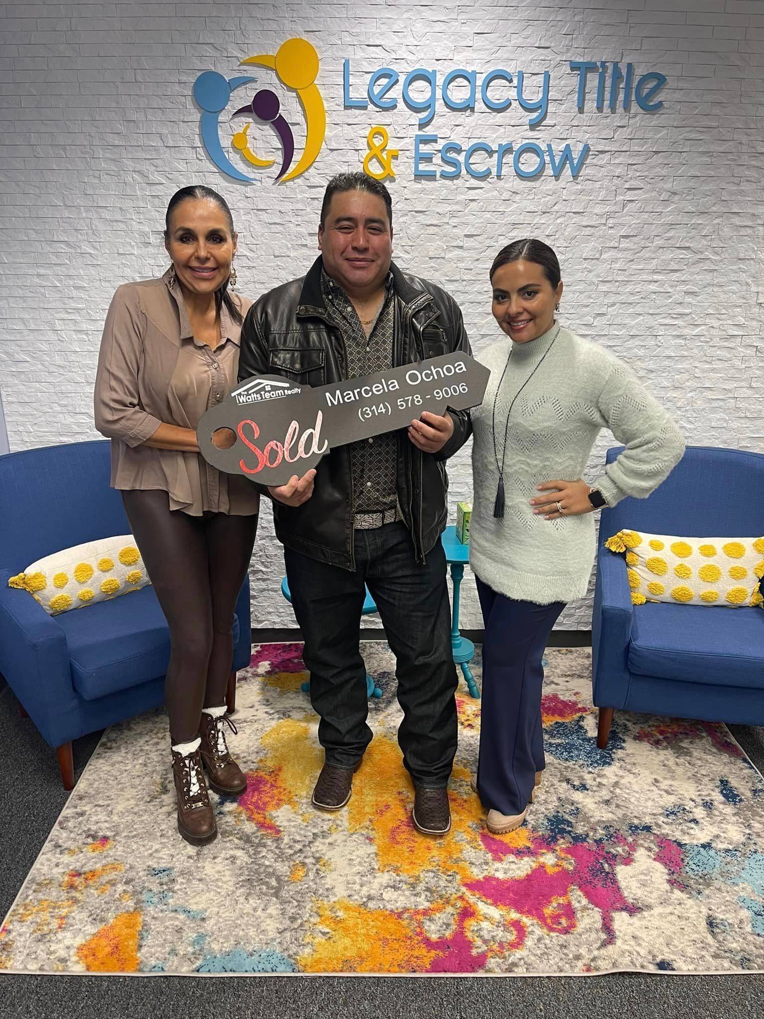 A man and two women are standing next to each other holding a key.