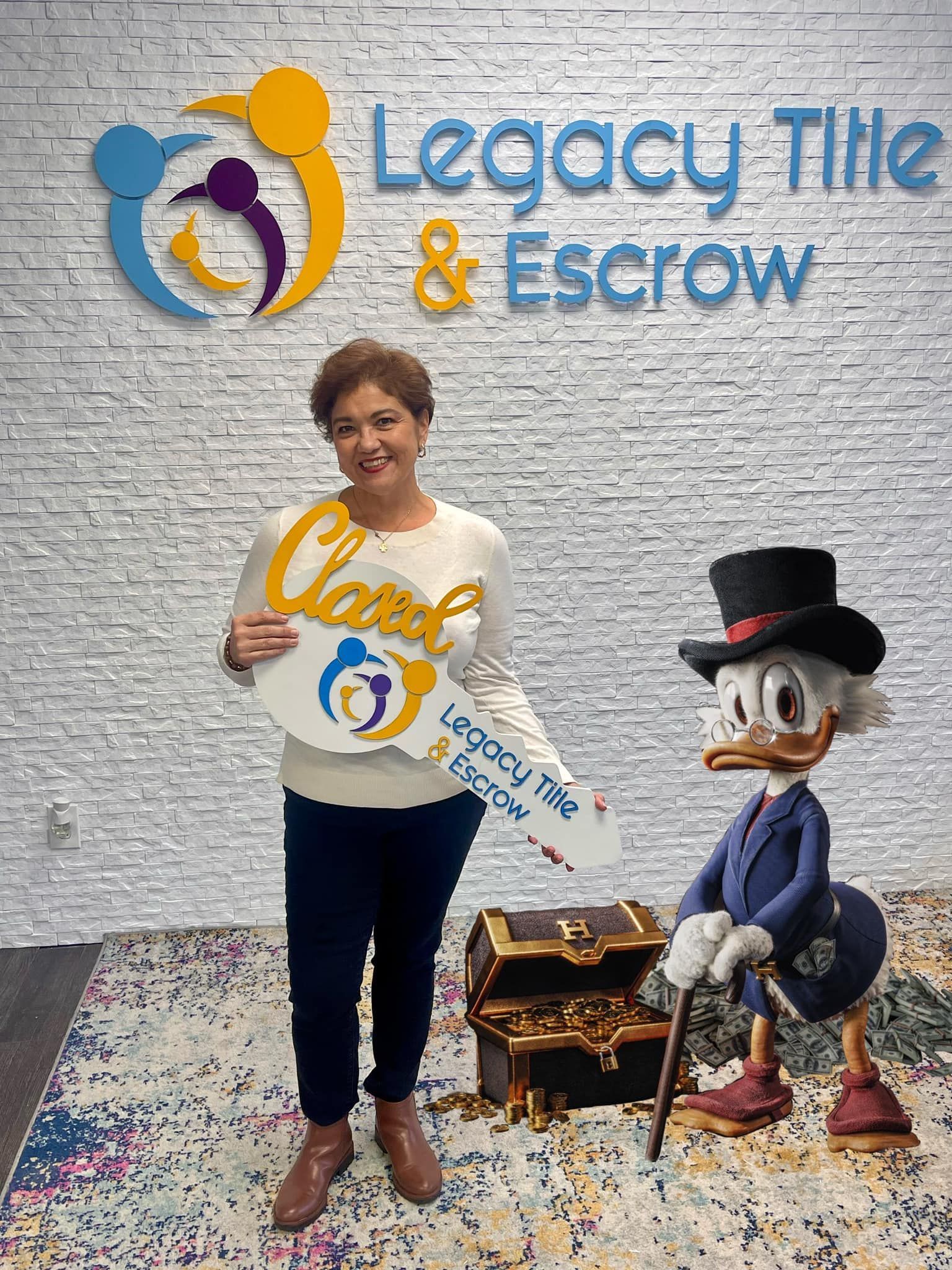 A woman is standing in front of a brick wall holding a key next to a statue of a duck.