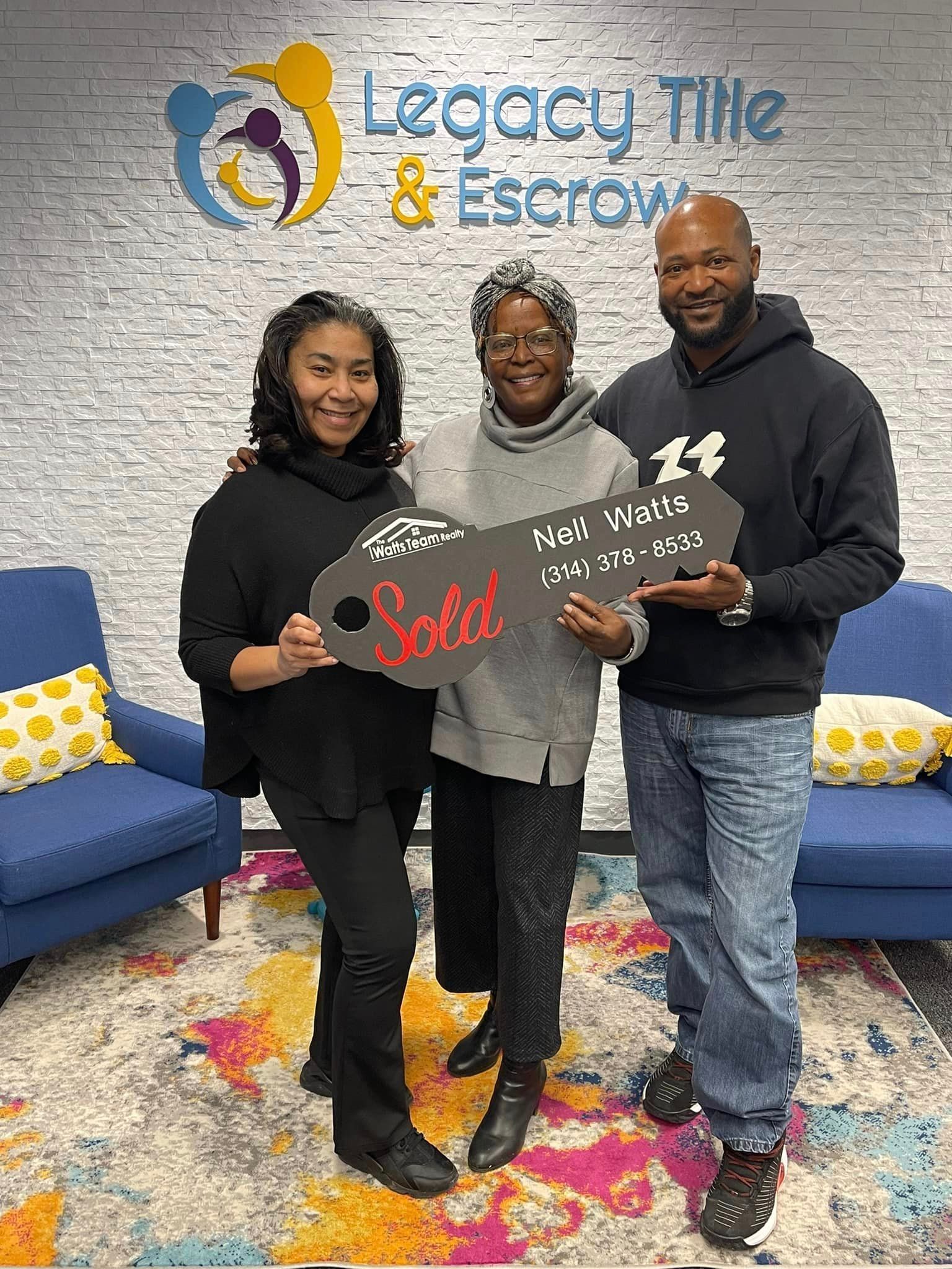 A group of people are standing next to each other holding a sold key.