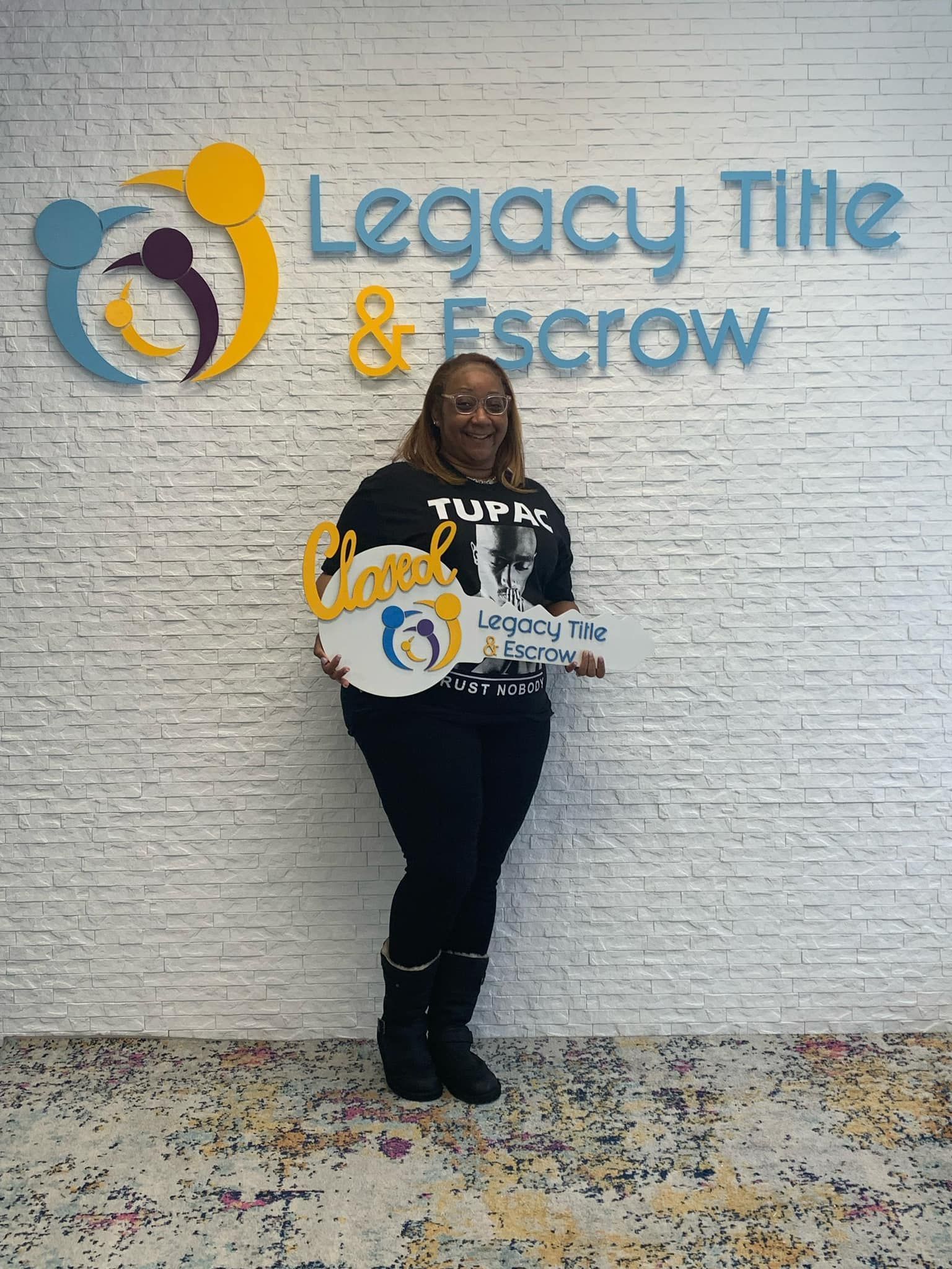 A woman is standing in front of a brick wall holding a sign.
