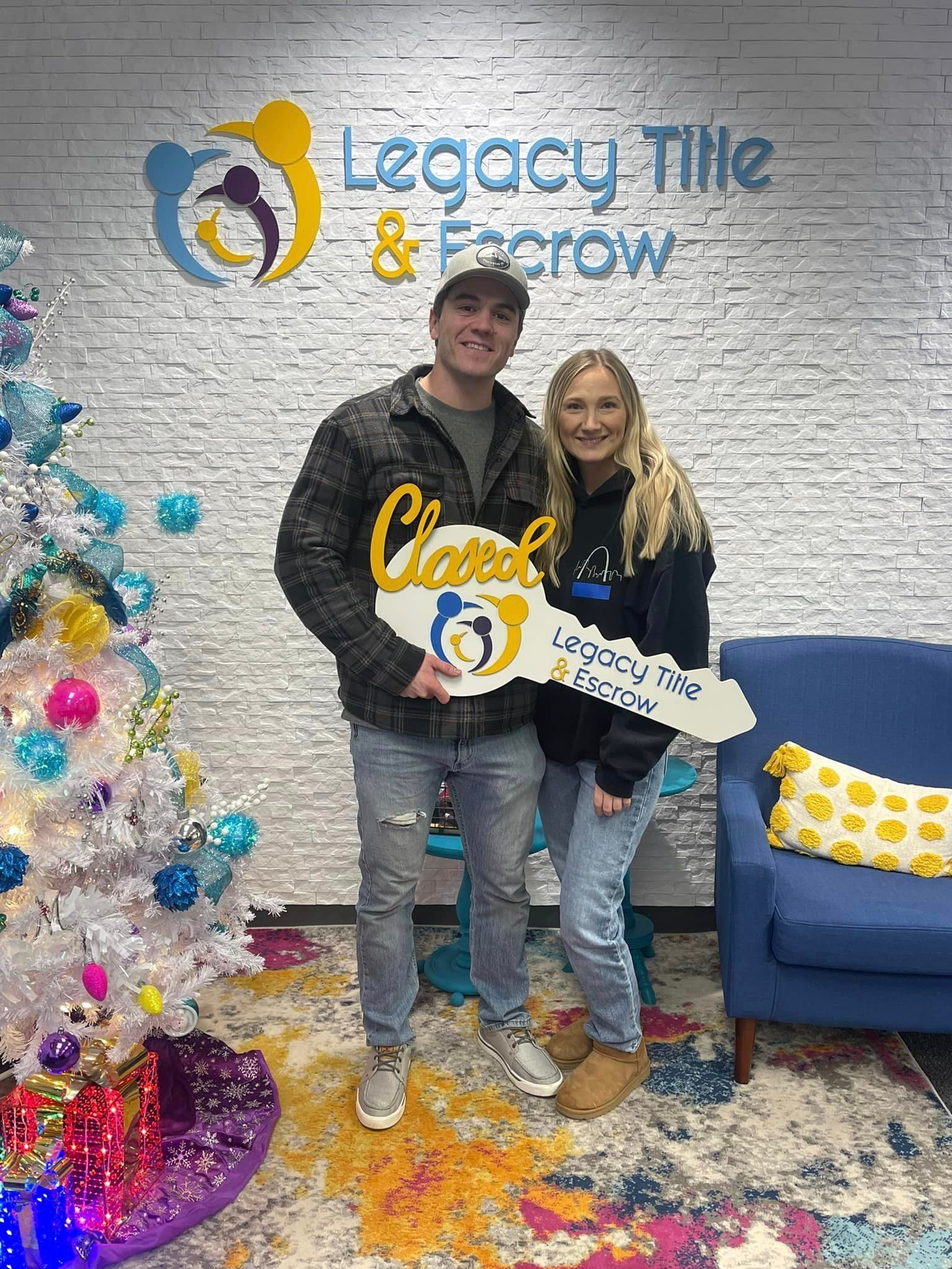 A man and a woman are holding a key in front of a christmas tree.