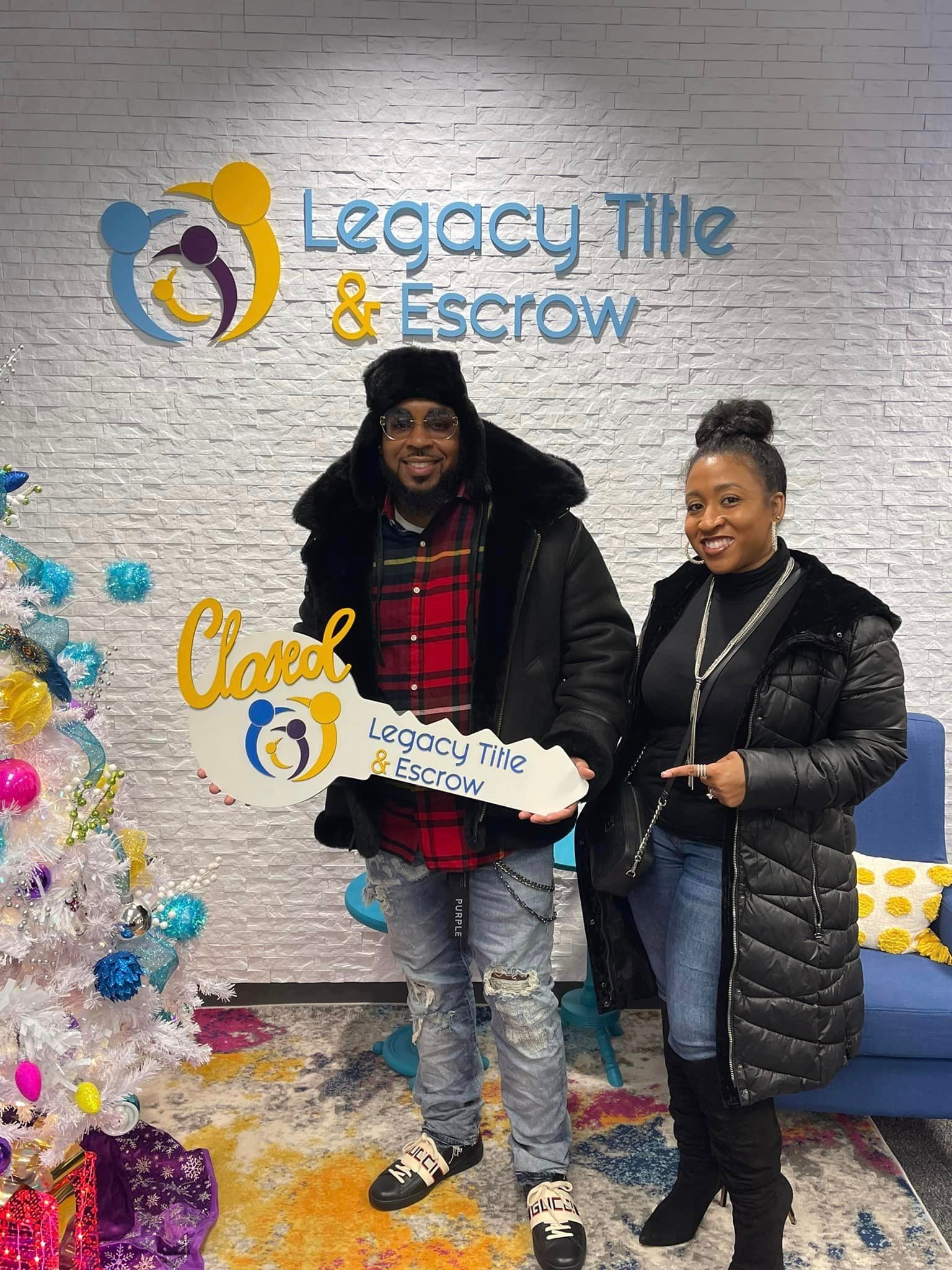 A man and a woman are standing next to each other in front of a christmas tree.