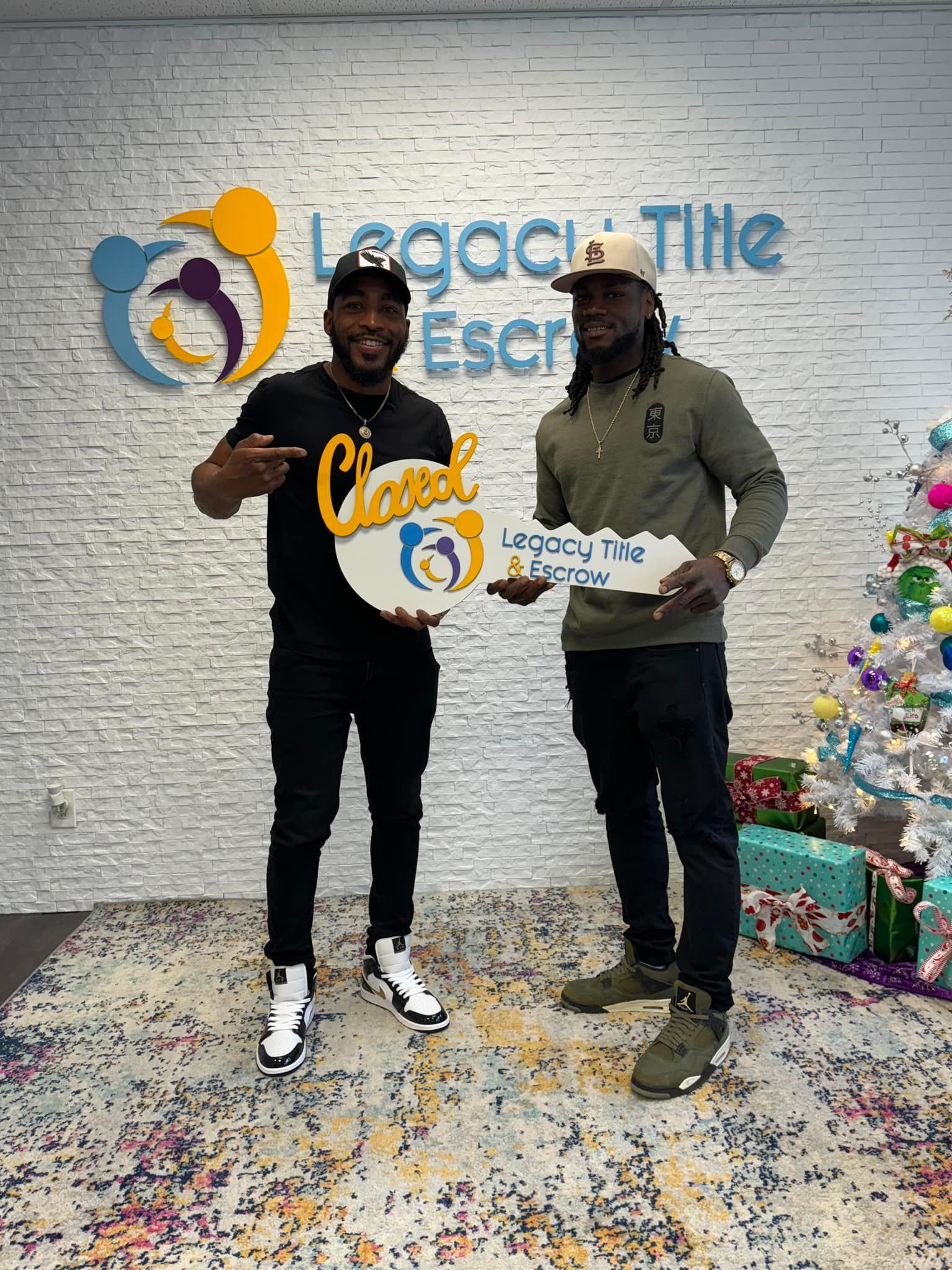 Two men are standing next to each other holding keys in front of a brick wall.