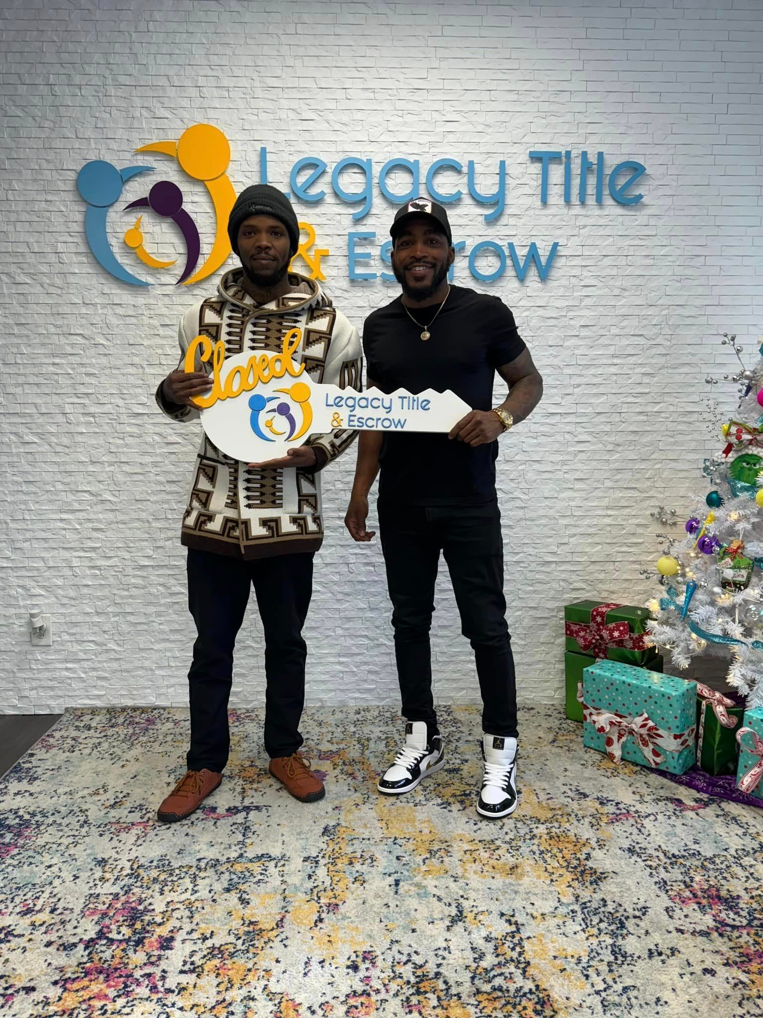 Two men are standing next to each other holding keys in front of a brick wall.