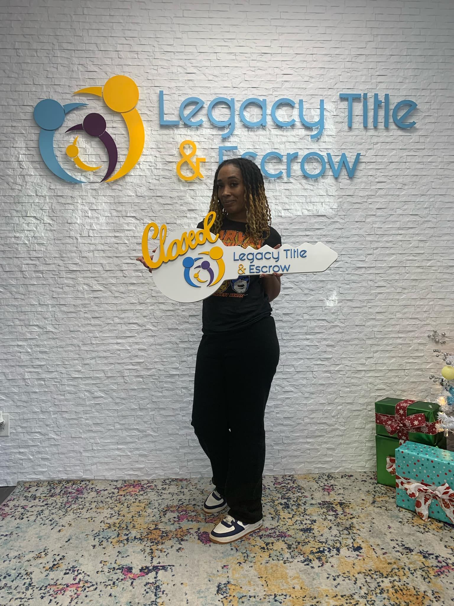 A woman is standing in front of a brick wall holding two keys.