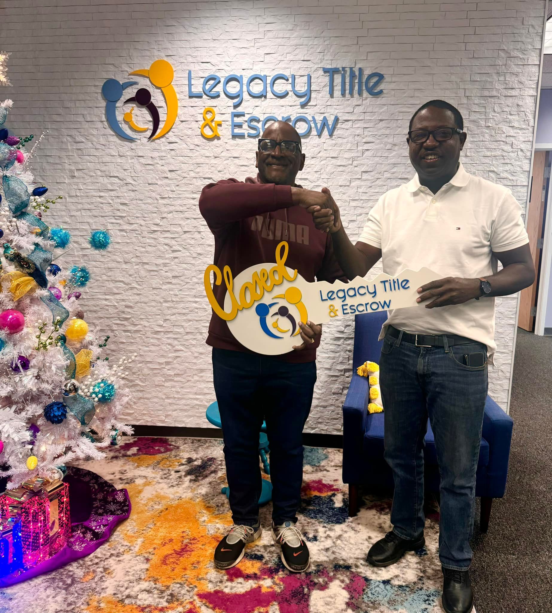 Two men are standing next to each other in front of a christmas tree.