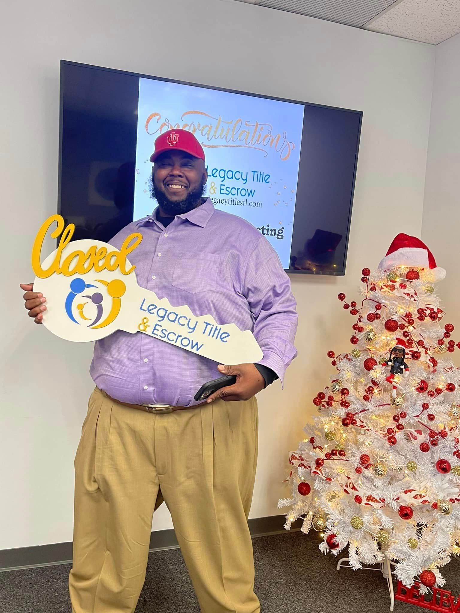 A man is holding a key in front of a christmas tree.