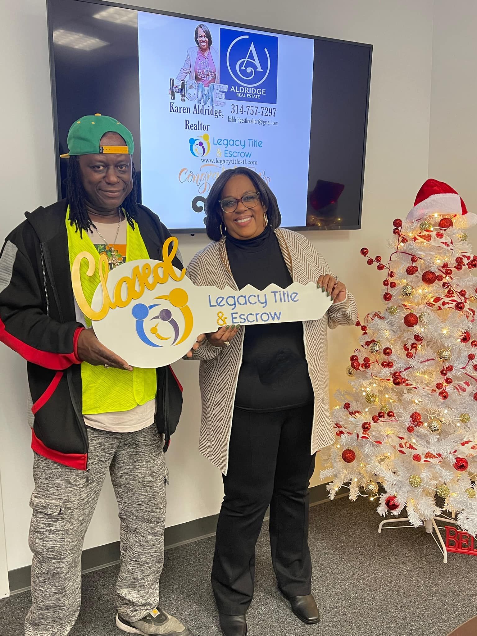 A man and a woman are holding a key in front of a christmas tree.