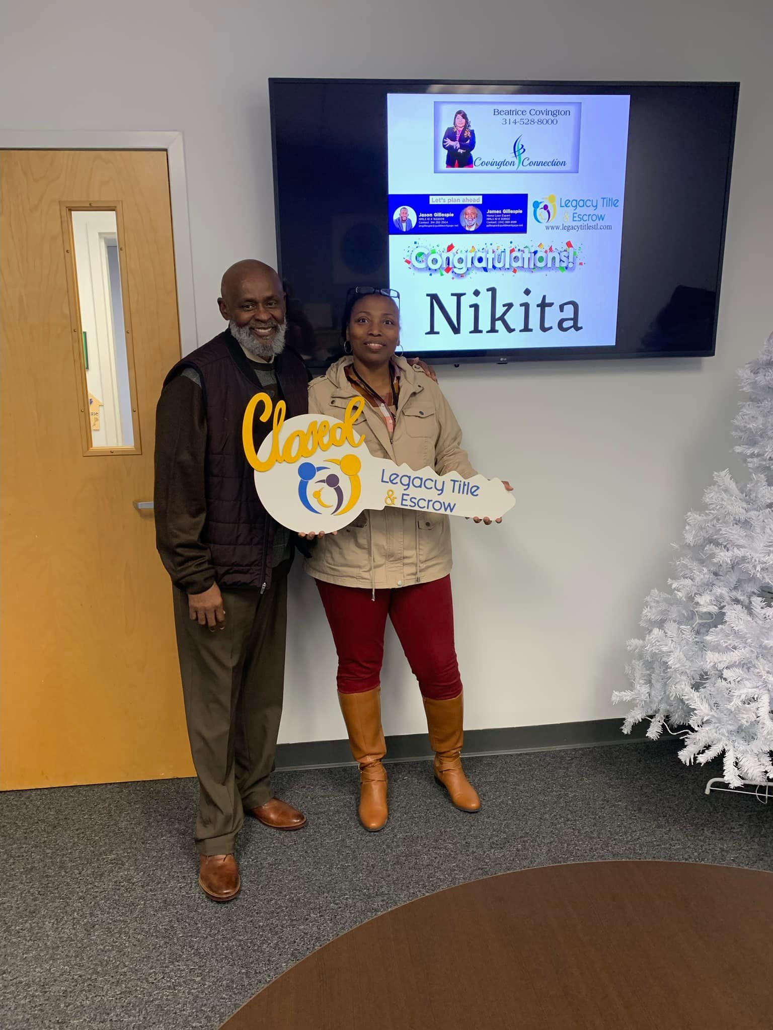 A man and a woman are standing next to each other holding a large key.