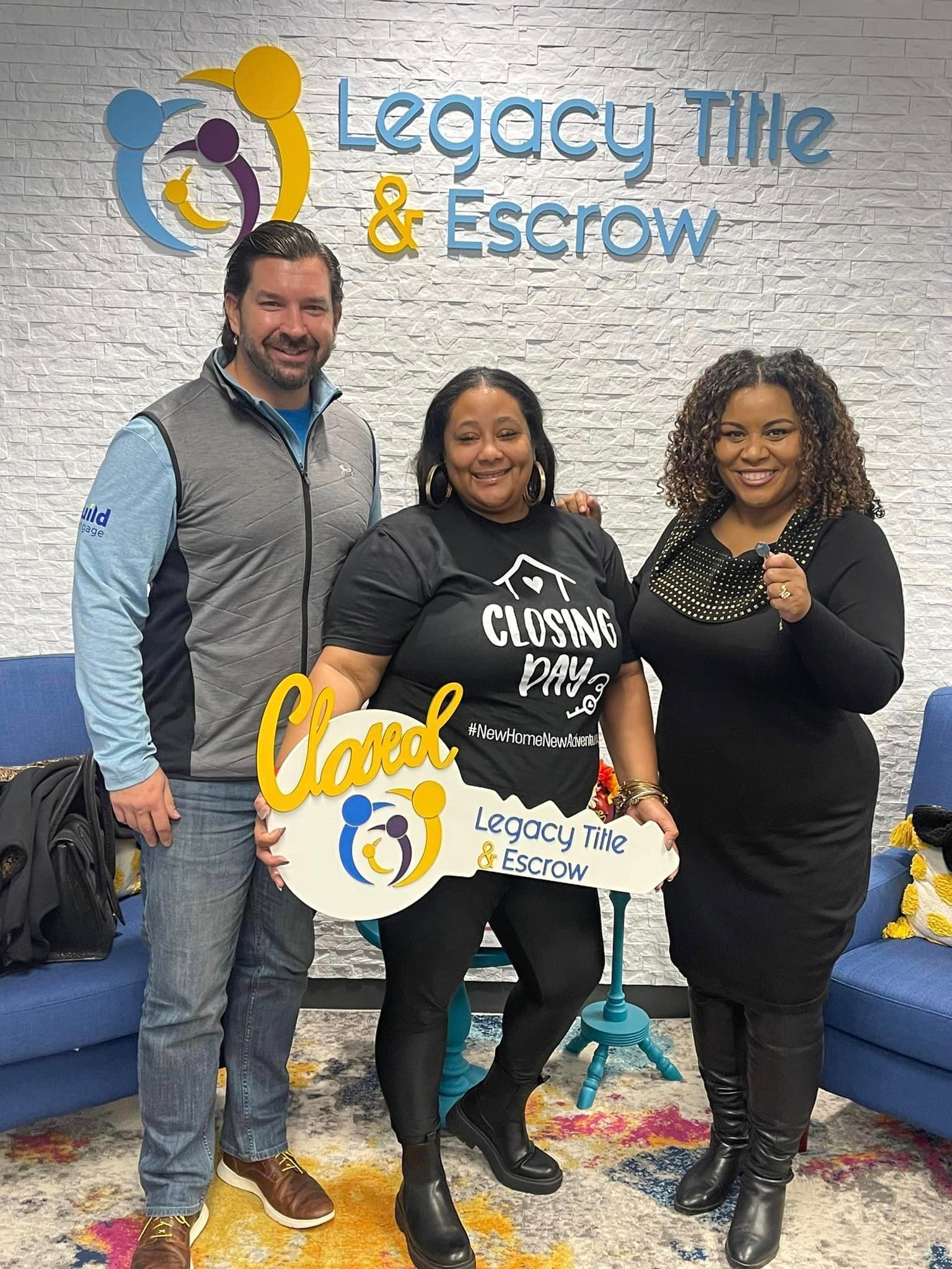 A man and two women are standing next to each other holding a large key.