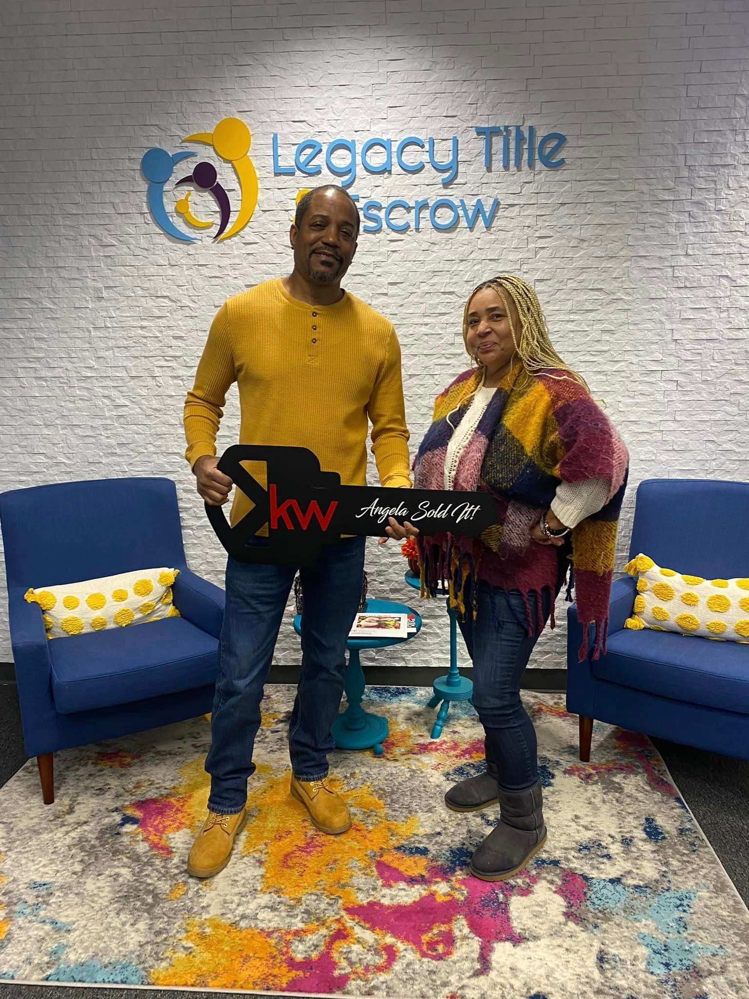 A man and a woman are standing next to each other in a living room holding a key.