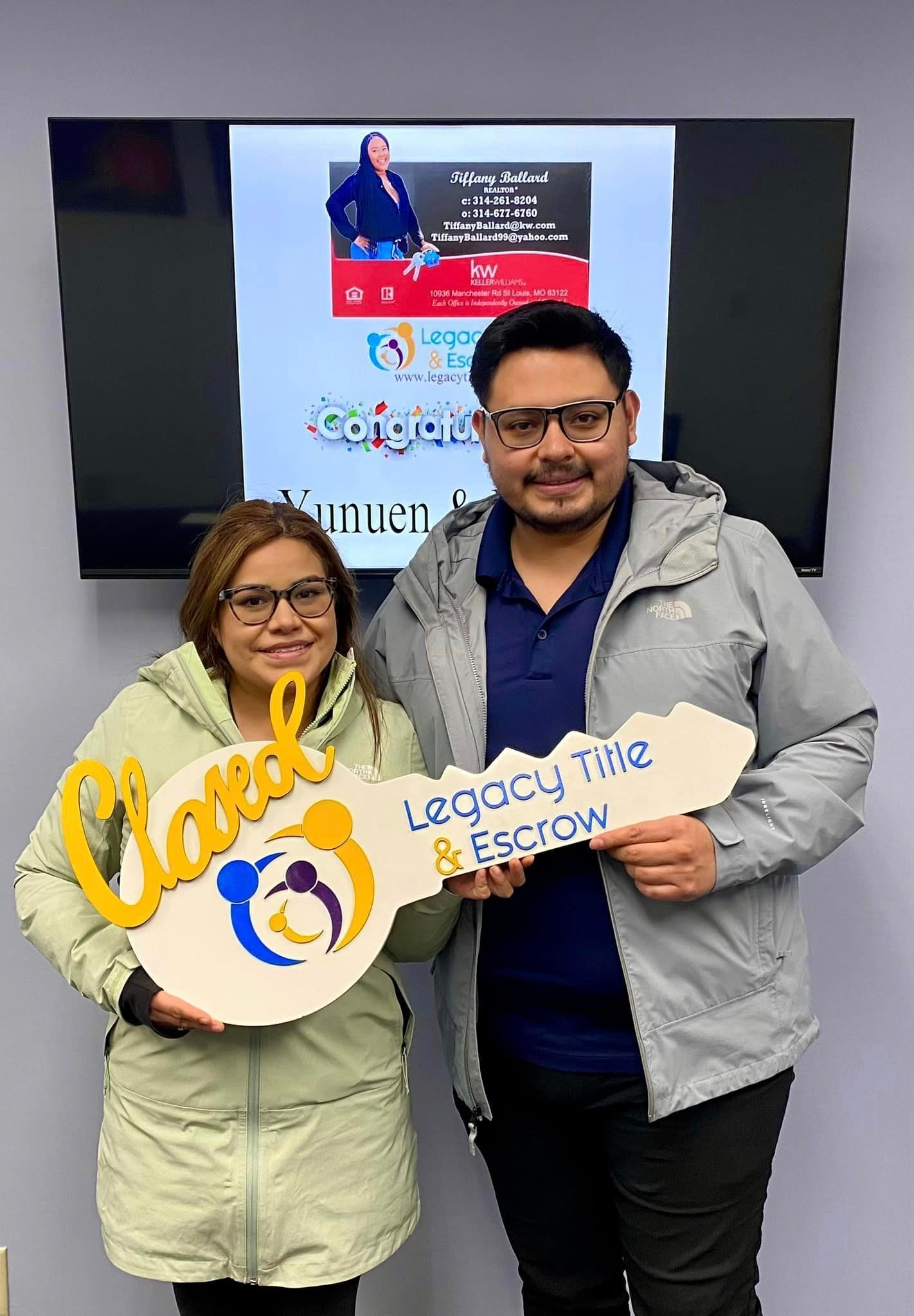 A man and a woman are holding a key in front of a television.