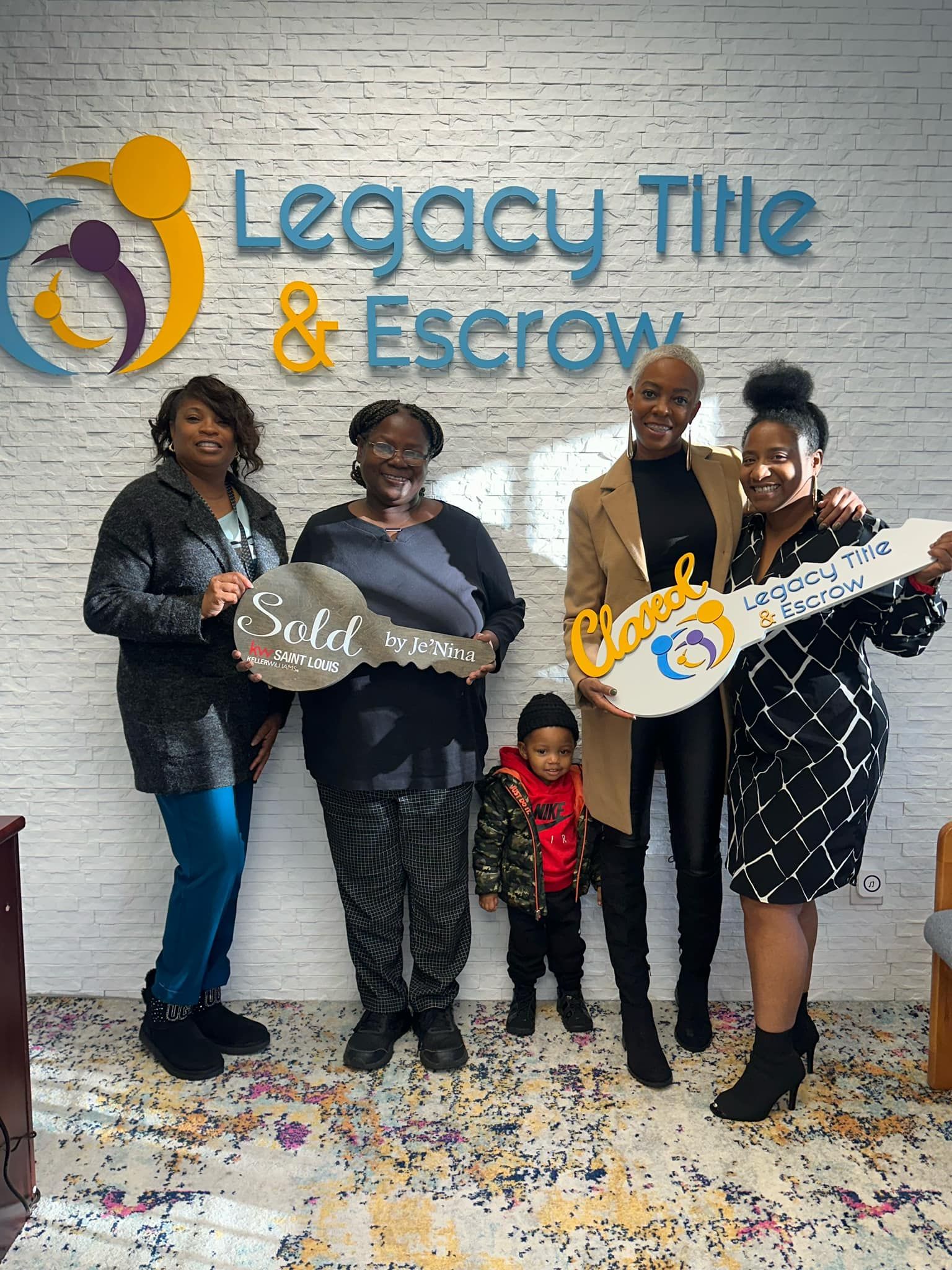 A group of people standing next to each other holding keys in front of a legacy title and escrow sign.