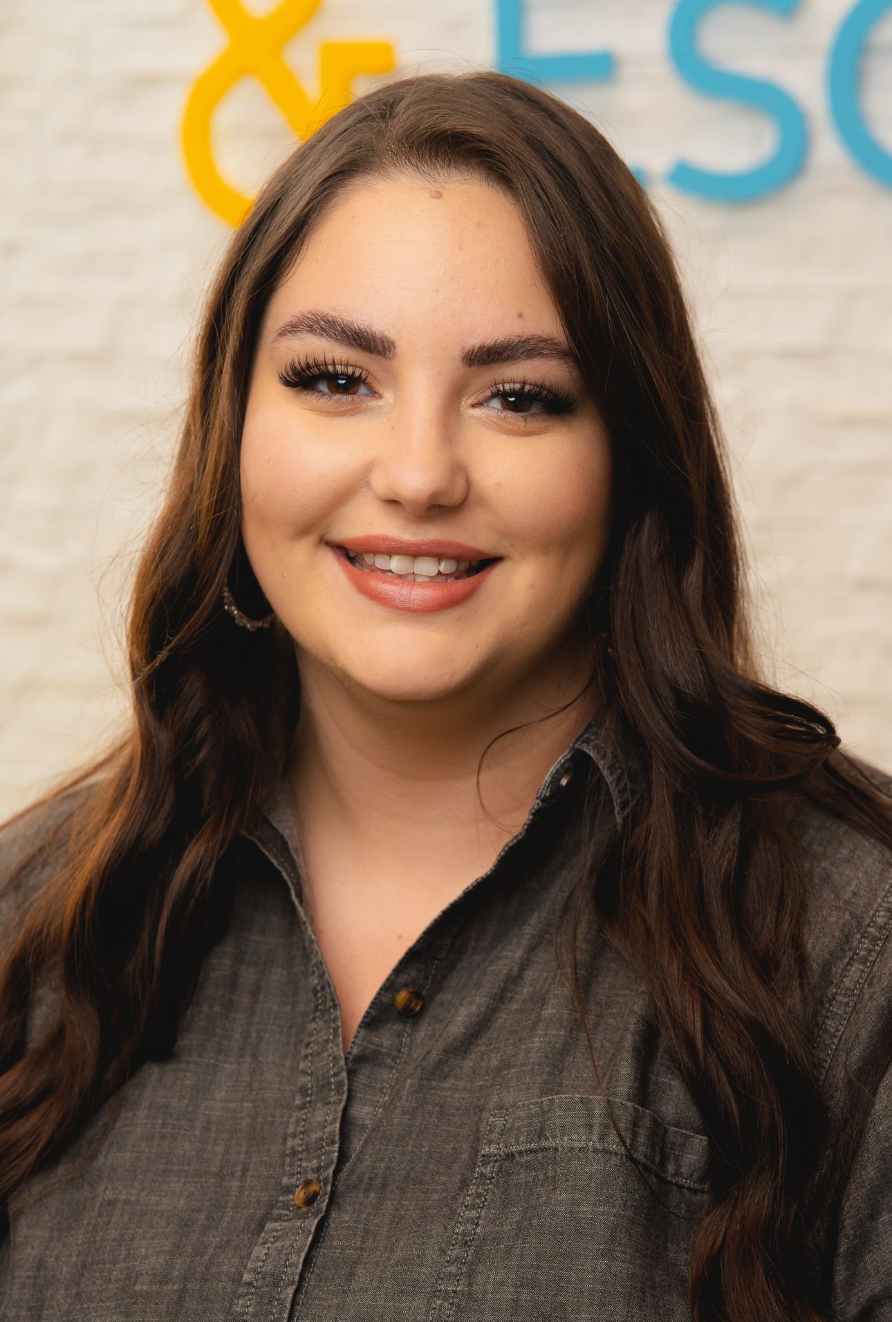 A woman in a grey shirt is smiling for the camera