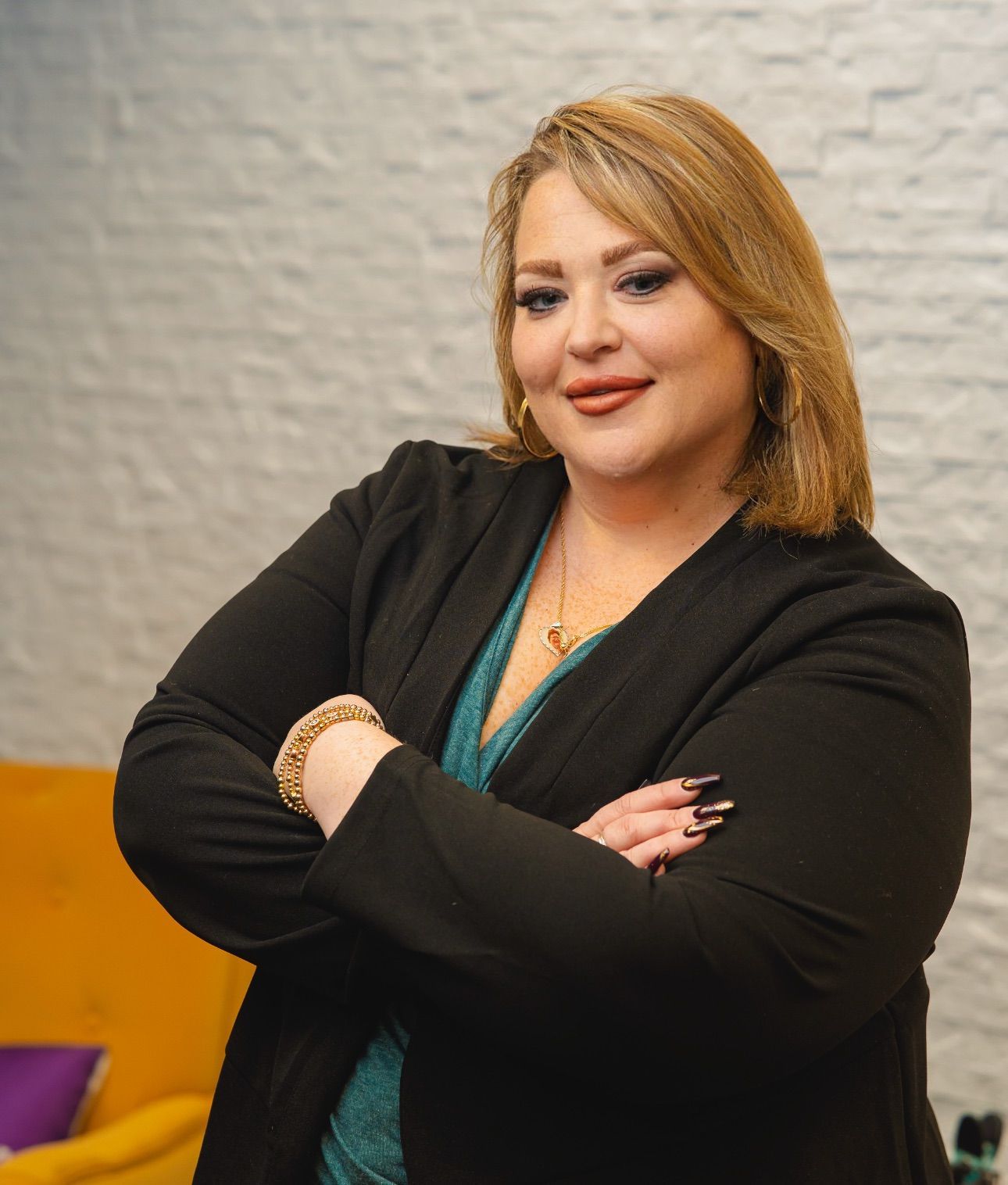 A woman is standing with her arms crossed and smiling for the camera