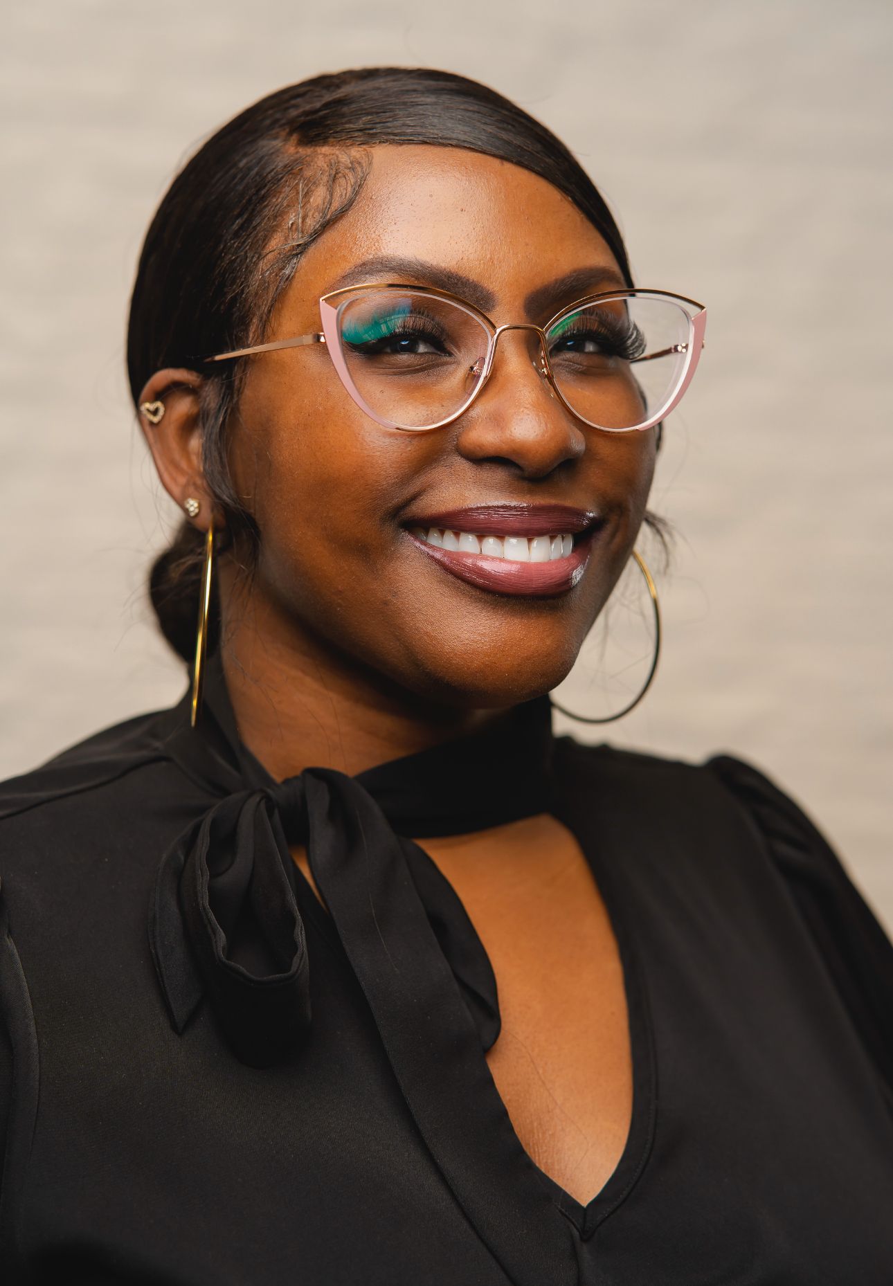 A woman wearing glasses and a black shirt is smiling for the camera