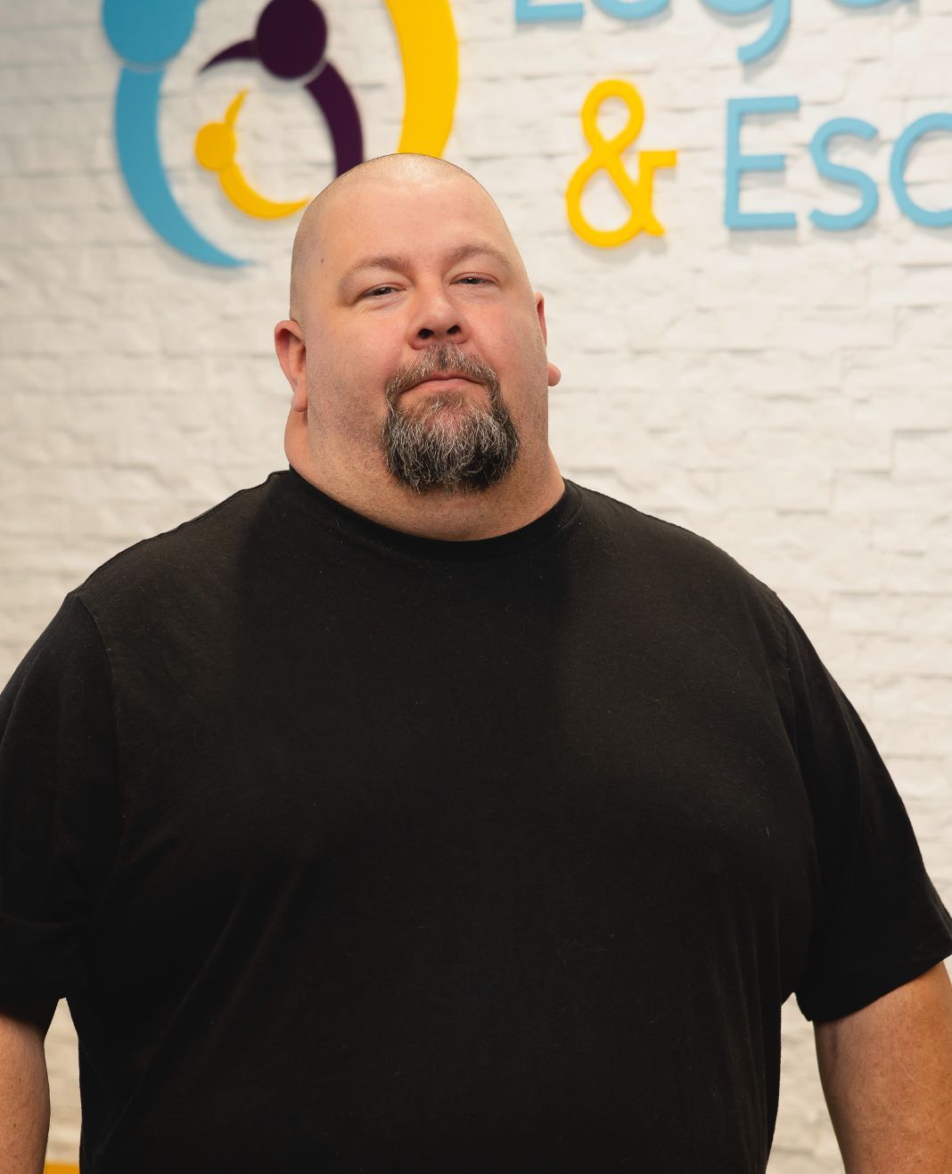 A bald man with a beard wearing a black shirt