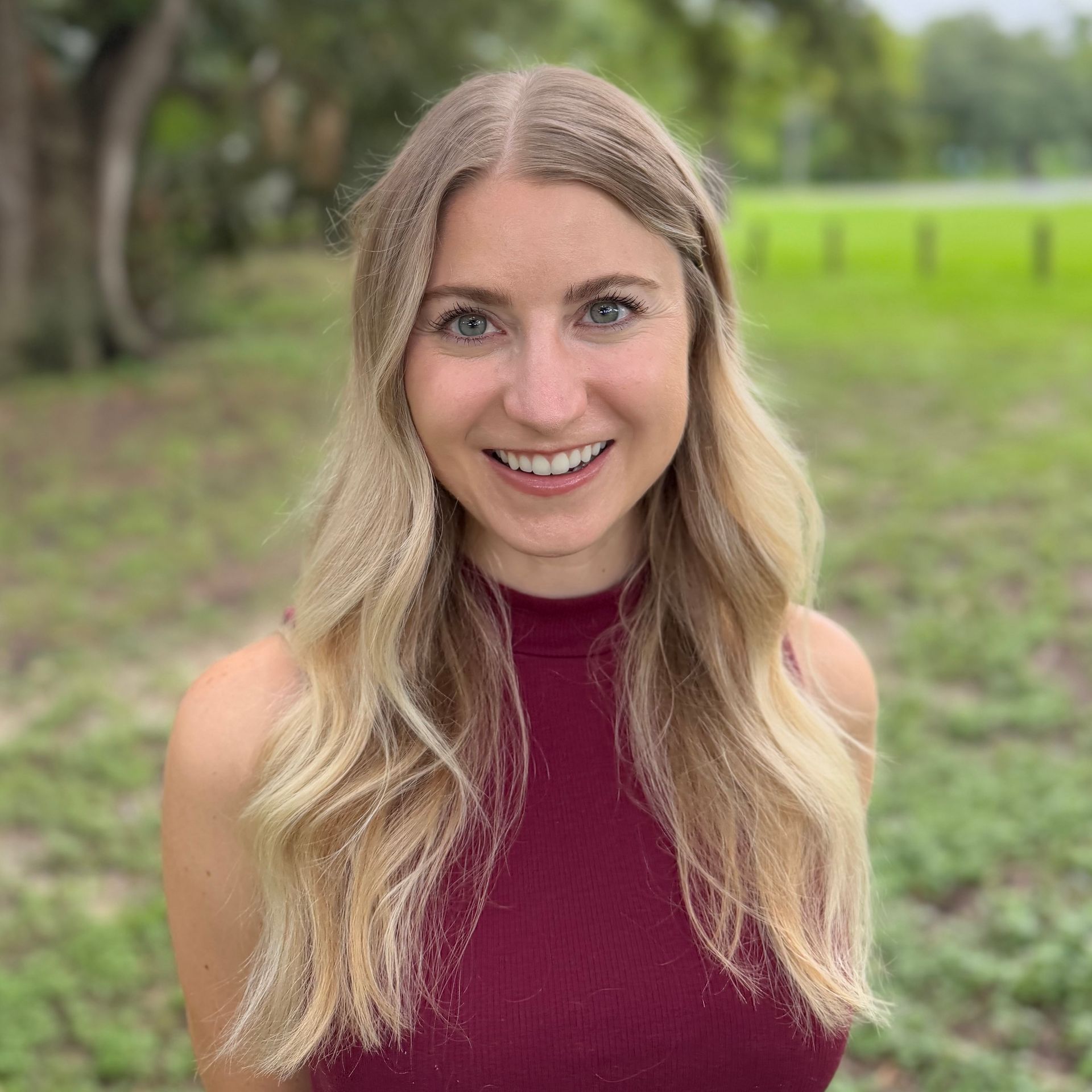 A woman with blonde hair and blue eyes is smiling for the camera.