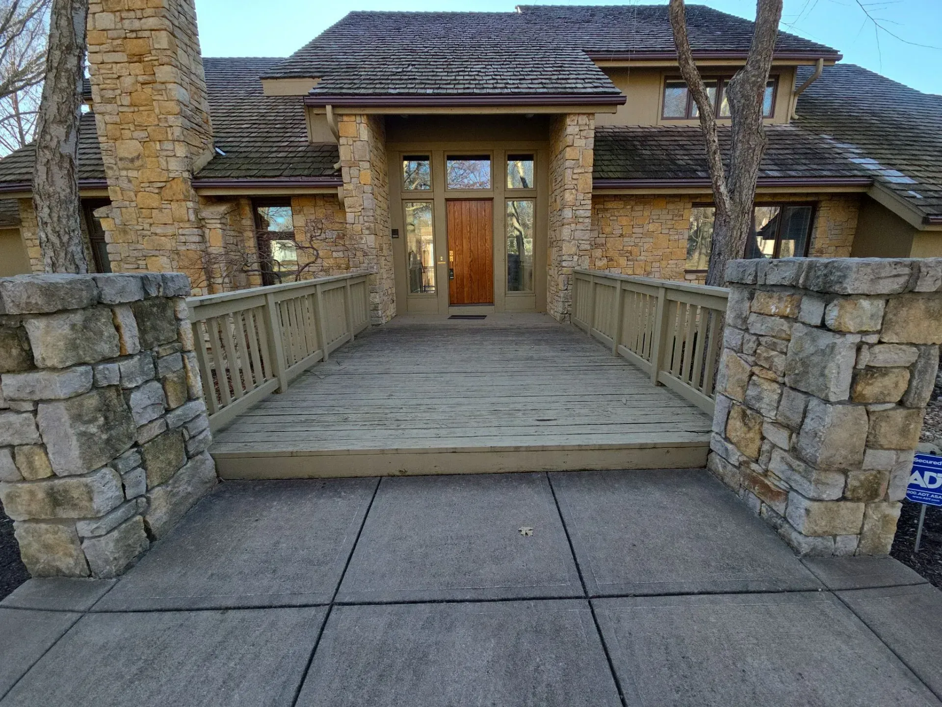 Stone and wood house exterior with a raised wooden walkway leading to the front door.
