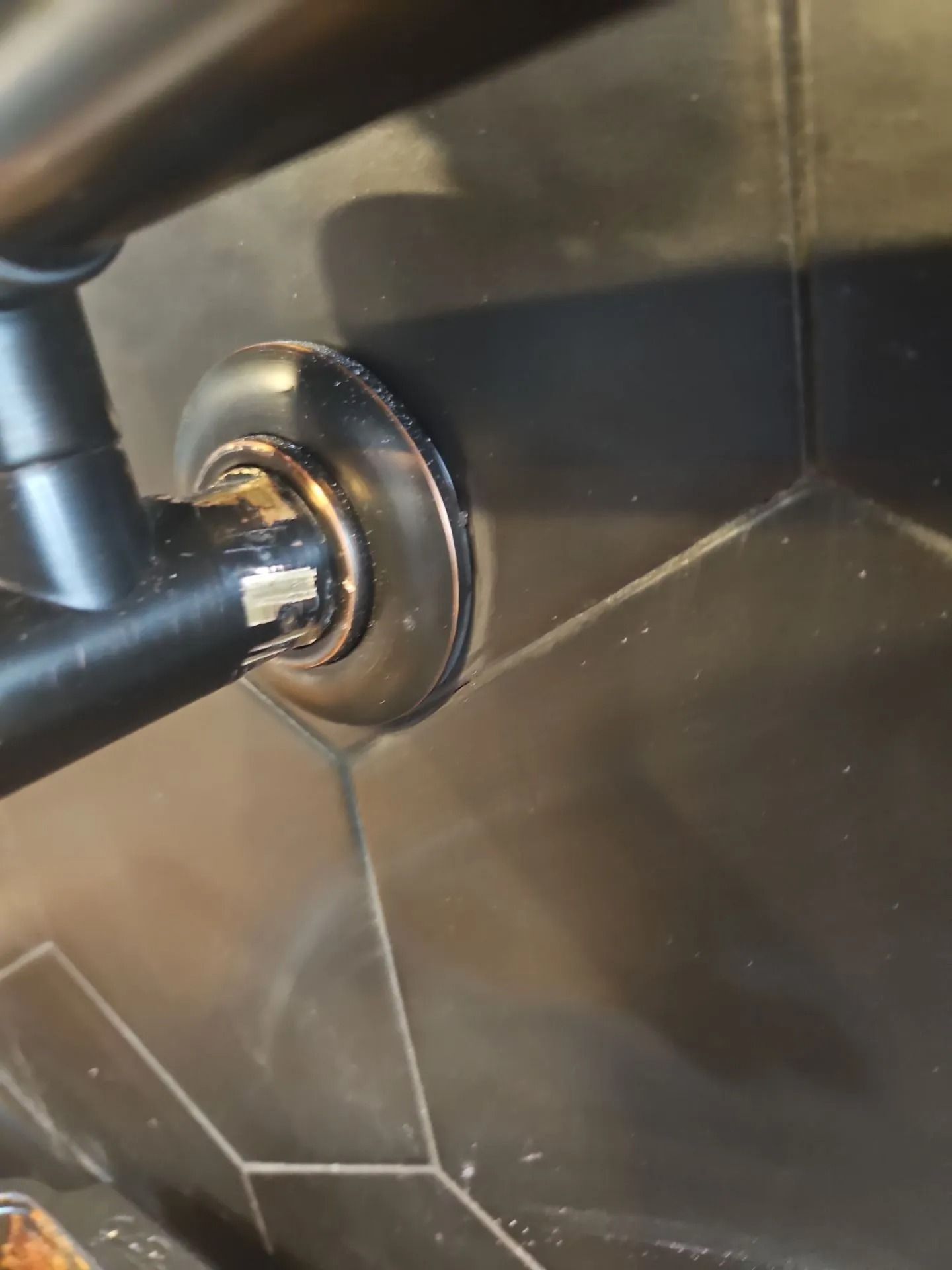 Black metal handrail attached to black, hexagonal tiles.