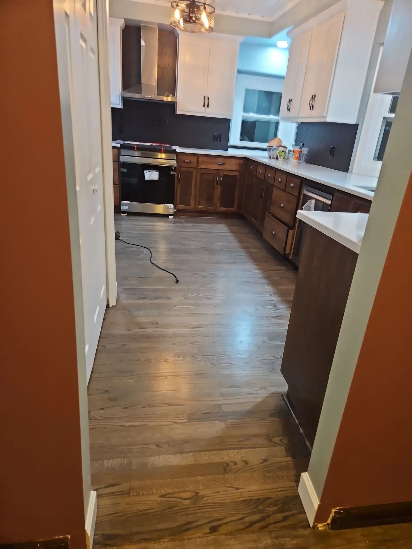 Newly renovated kitchen with dark wood cabinets, white countertops, and wood-look flooring.
