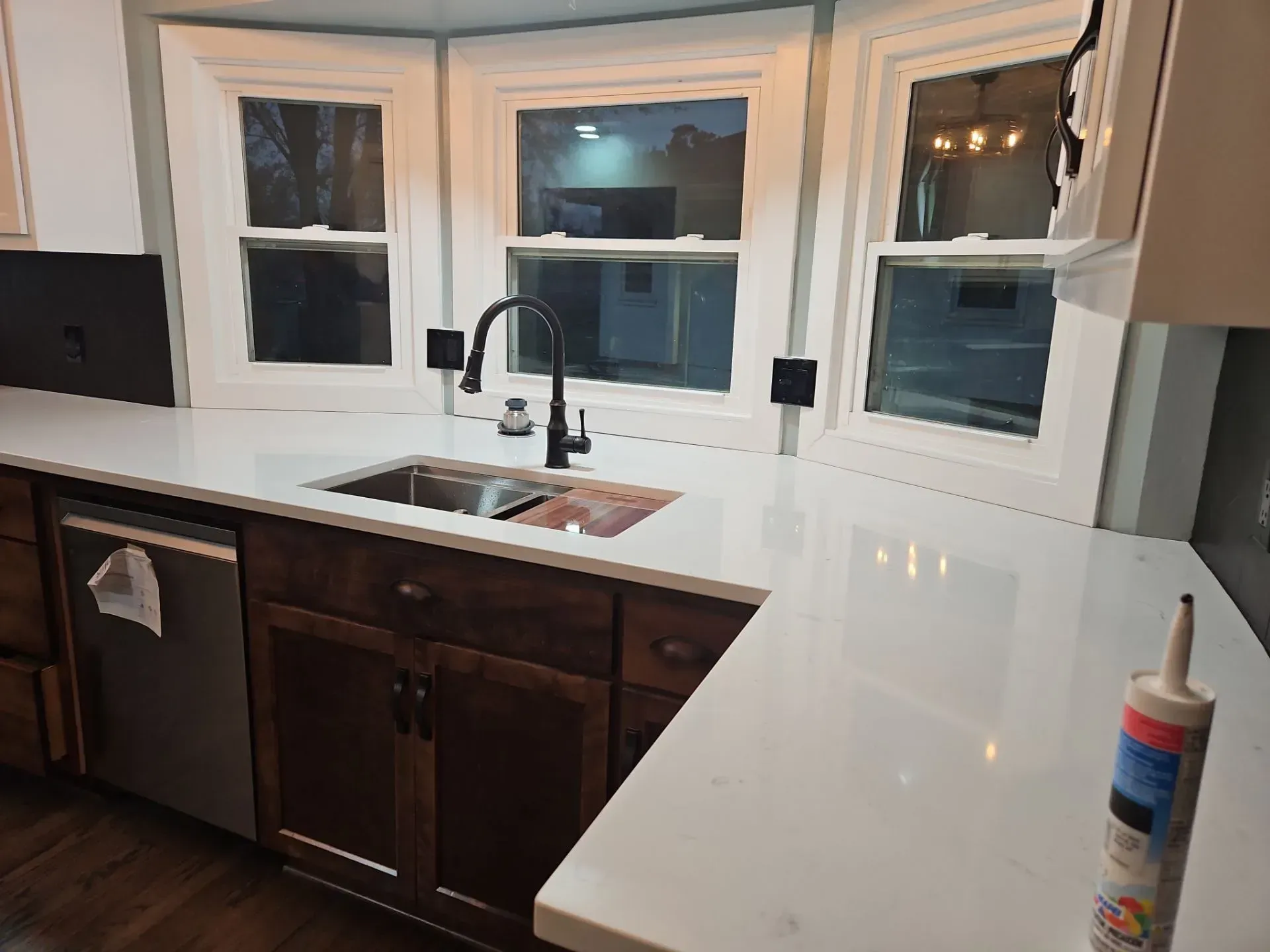 Kitchen with white countertops, dark wood cabinets, and a sink beneath a window.