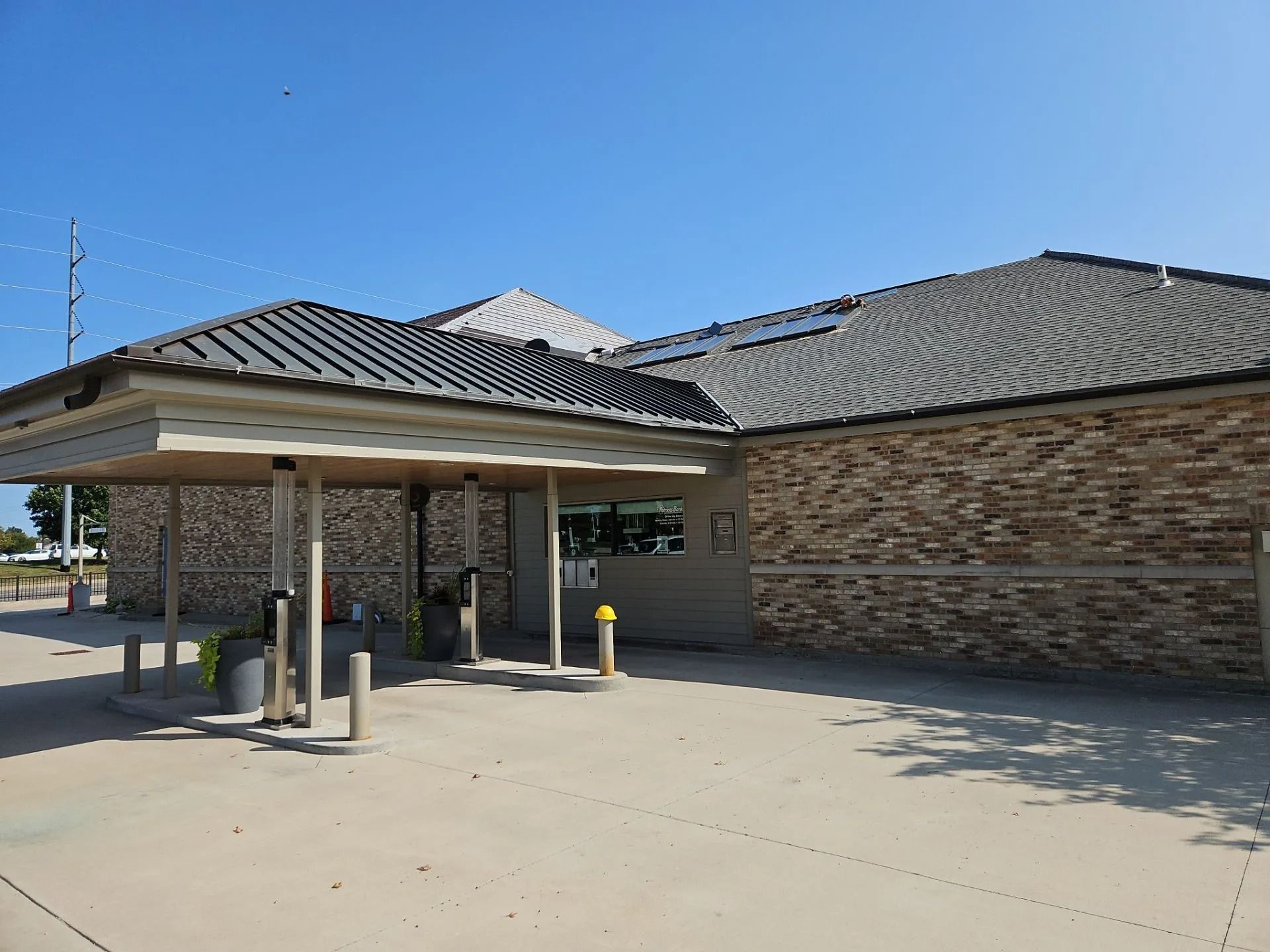 Exterior of a brick building with a covered drive-up area, under a blue sky.