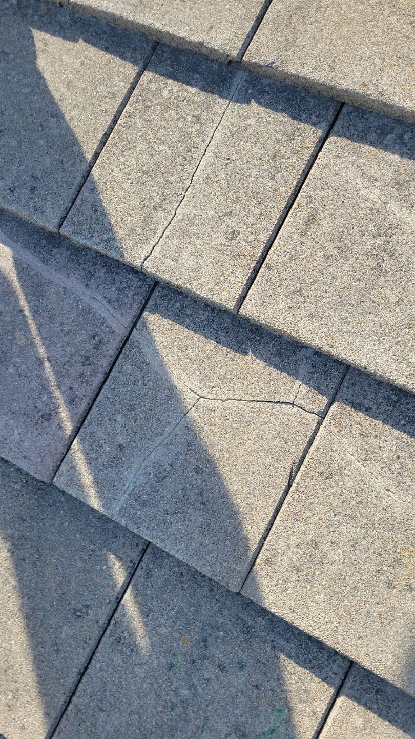 Close-up of gray roof tiles; one tile has a crack running through it.