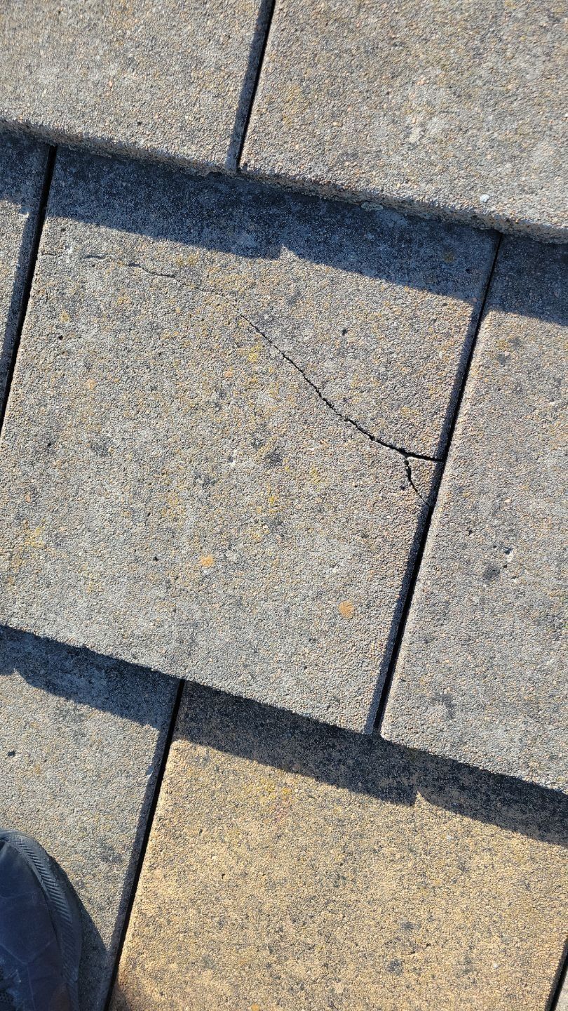 Close-up of cracked gray paving stone amidst similar stones.