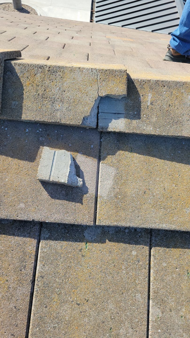 Close-up of a roof with missing and damaged shingles. Beige, weathered appearance.
