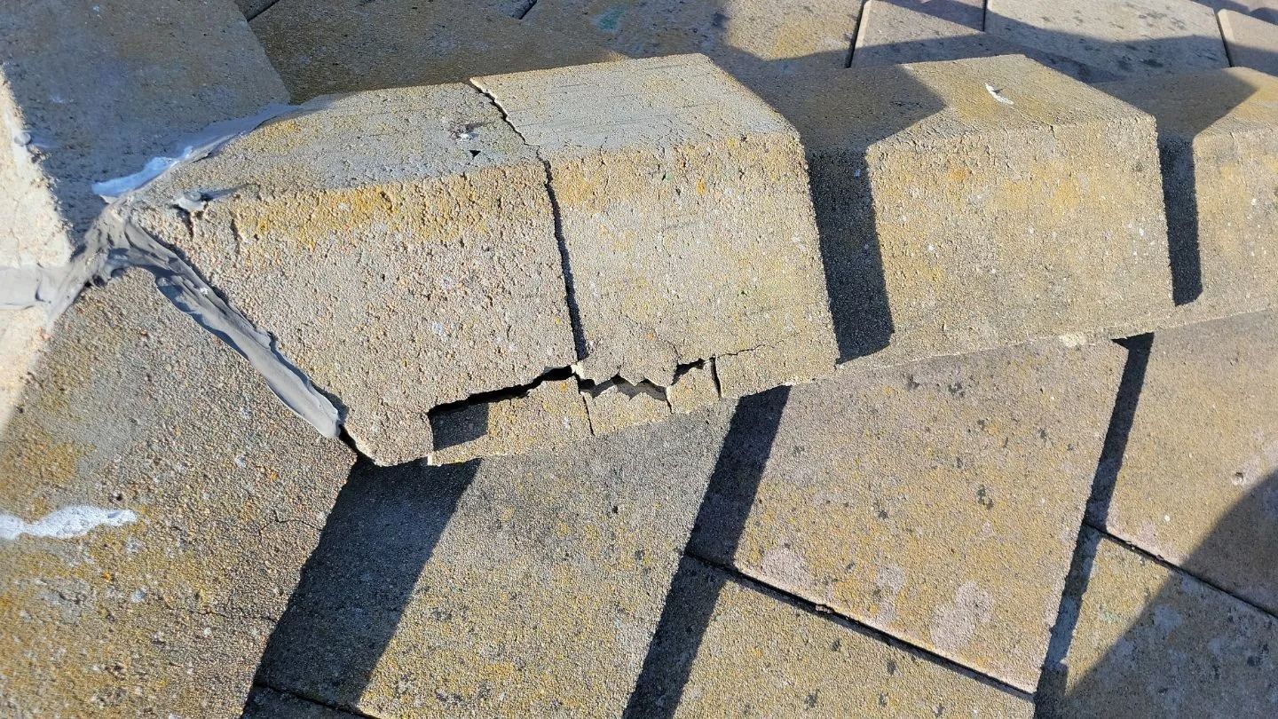 Close-up of cracked concrete blocks in a curved pattern on a surface.