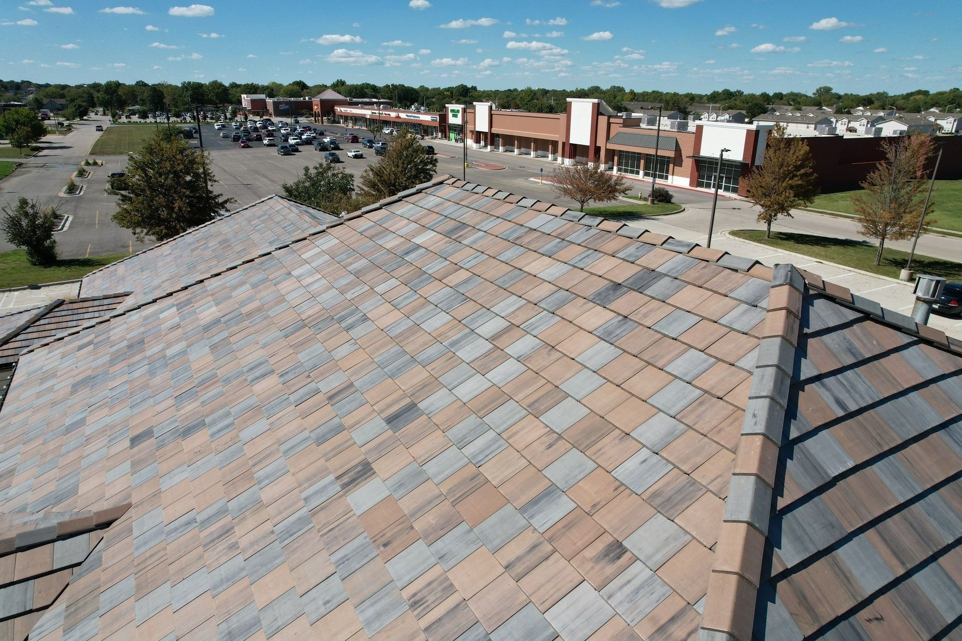 Rooftop with varied colored tiles, overlooking a shopping center on a sunny day.