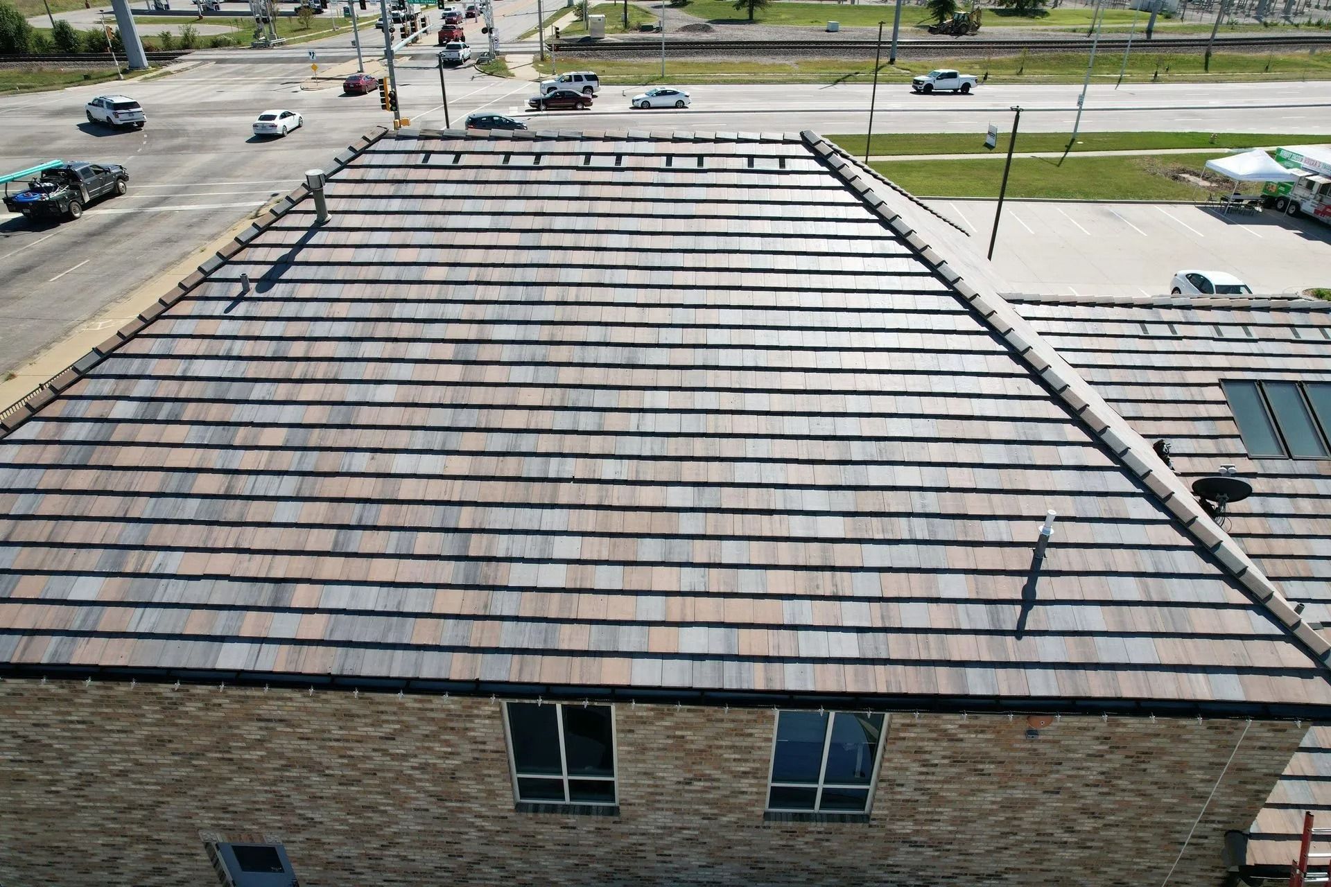 Rooftop view of a building with multi-colored tile roofing next to a busy street.